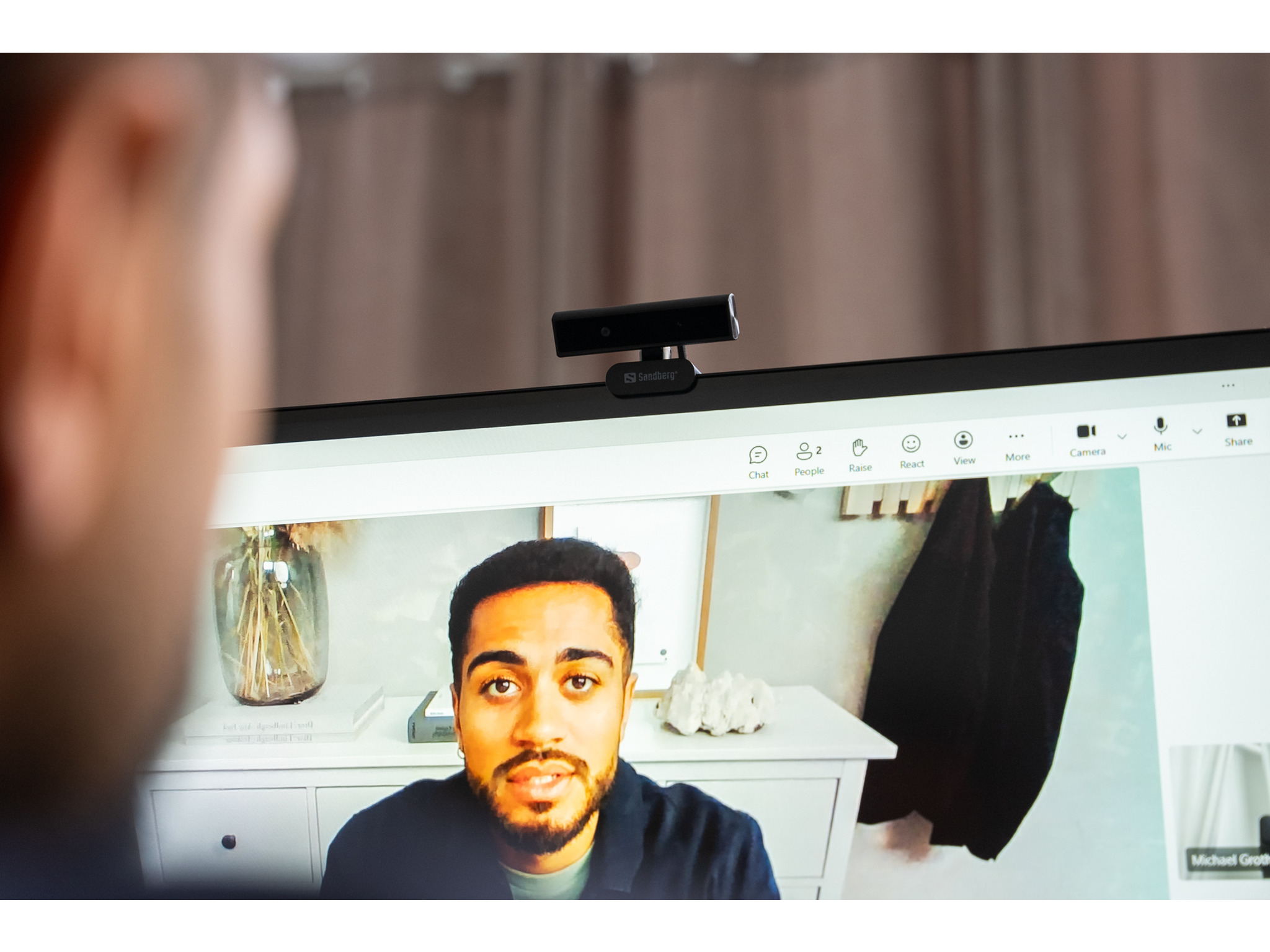 Osoba patrząca na monitor, na którym wyświetlana jest rozmowa wideo z kamerą internetową.