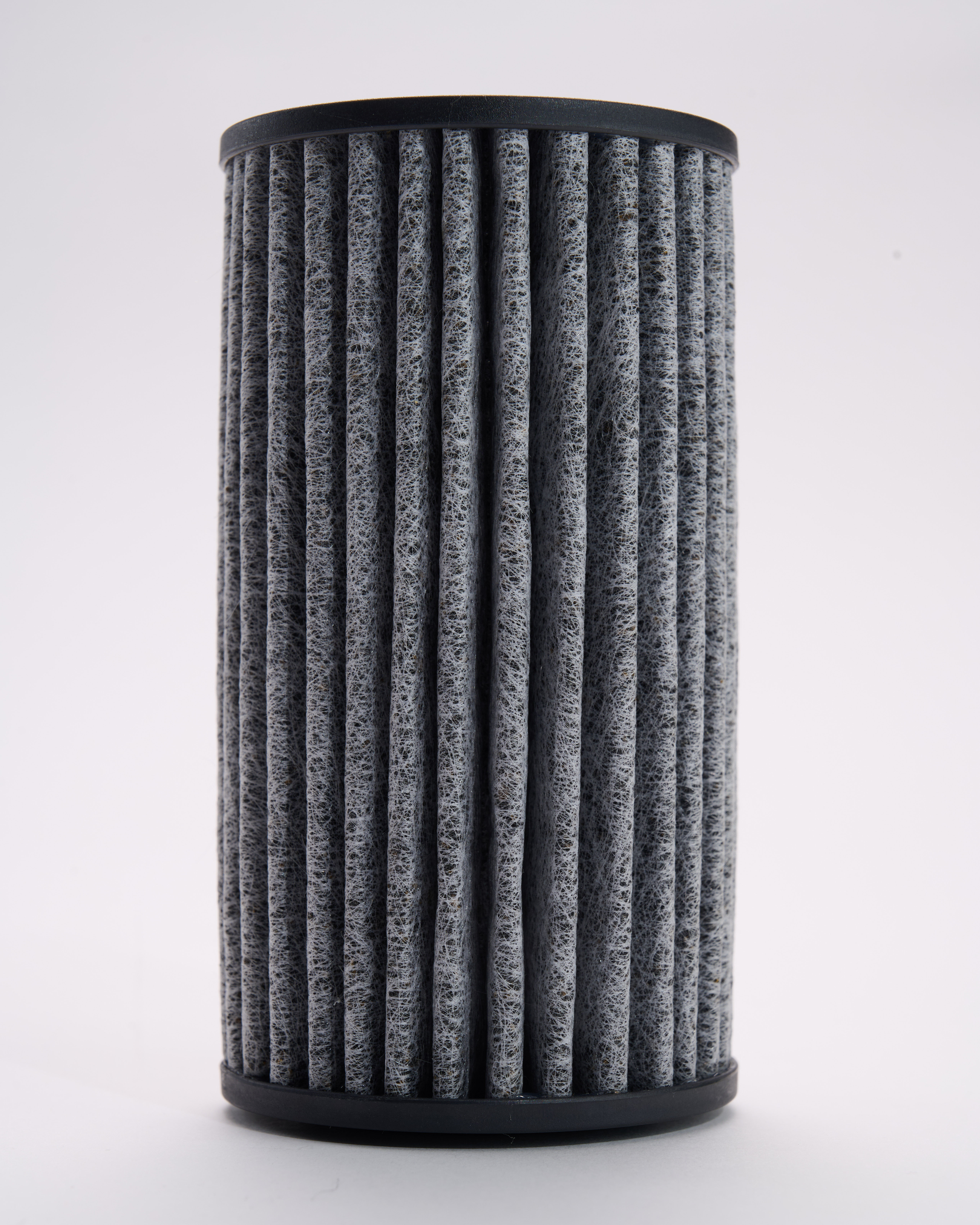 Ein zylindrischer Luftfilter mit grauem, plissiertem Material. Schwarzer Kunststoff oben und unten.