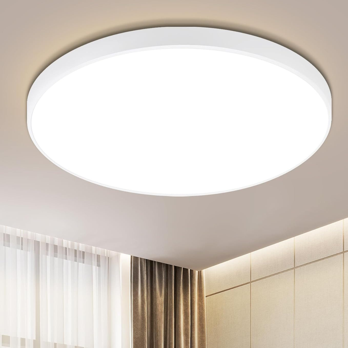 Una plafoniera rotonda bianca illumina una stanza. Sono visibili pareti beige, una tenda marrone e un soffitto bianco.