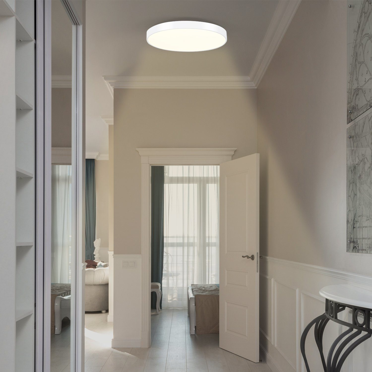 Corridoio con una luce a soffitto rotonda. C'è una porta, uno specchio e pareti bianche con modanature.