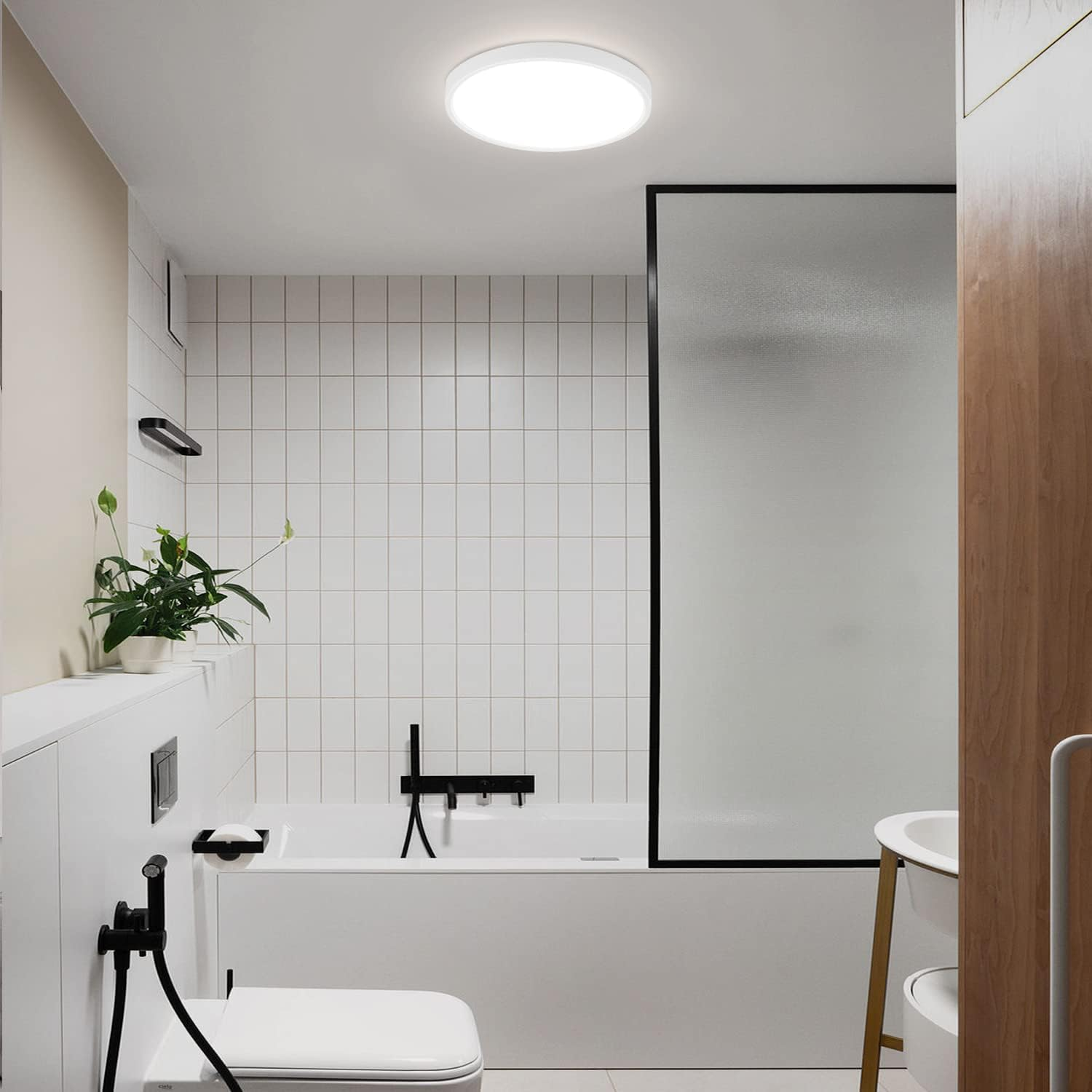 Un bagno piastrellato bianco con doccia, vasca da bagno e una pianta verde.