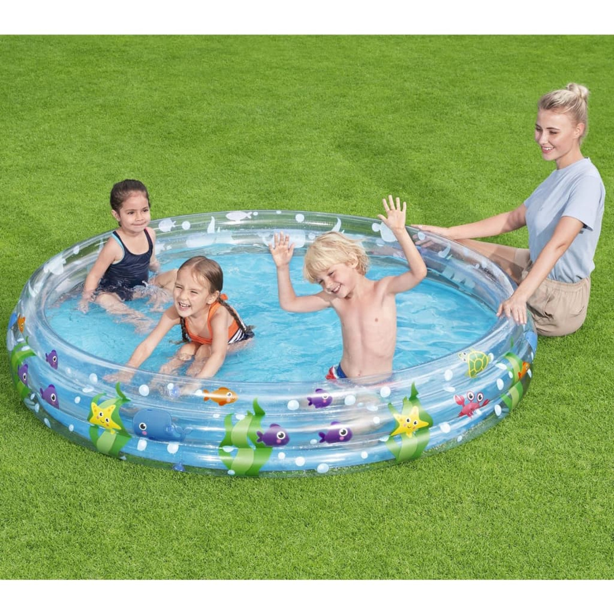Bambini che giocano in piscina, una donna guarda. Sfondo di erba verde.