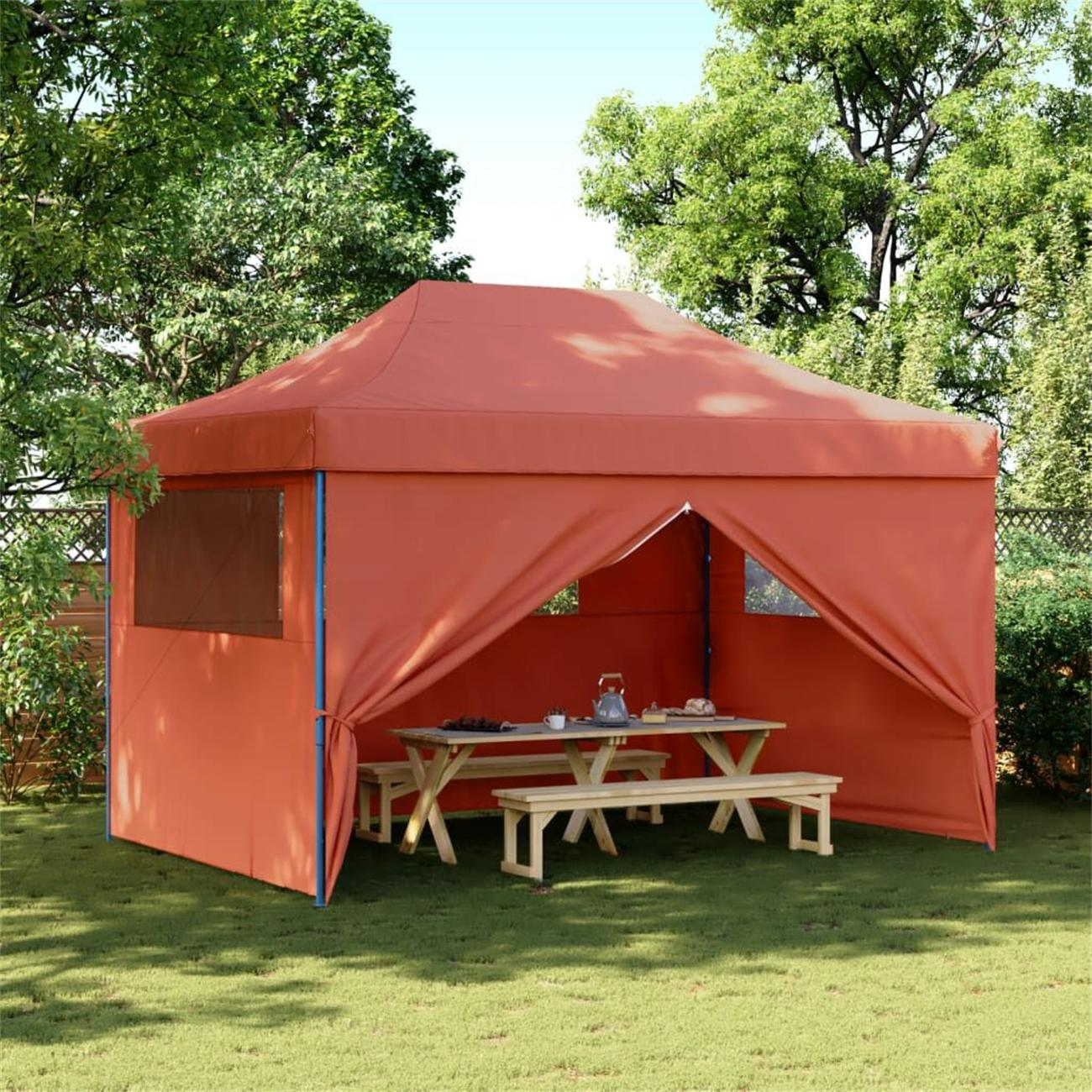 Orangener Pavillon auf Gras mit Tisch und Bänken, umgeben von grünen Bäumen.