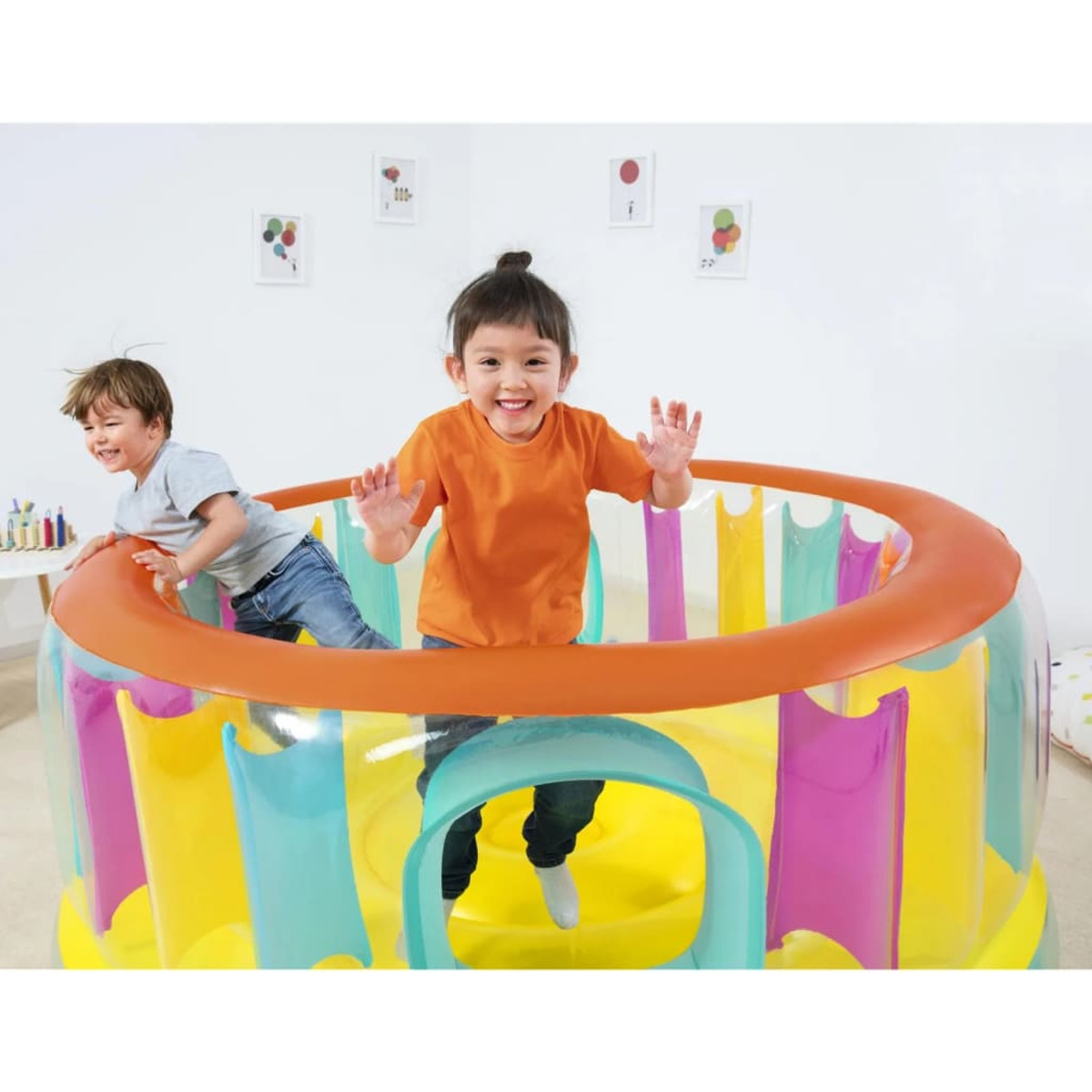 Zwei Kinder spielen in einem bunten, aufblasbaren Hüpfhaus.