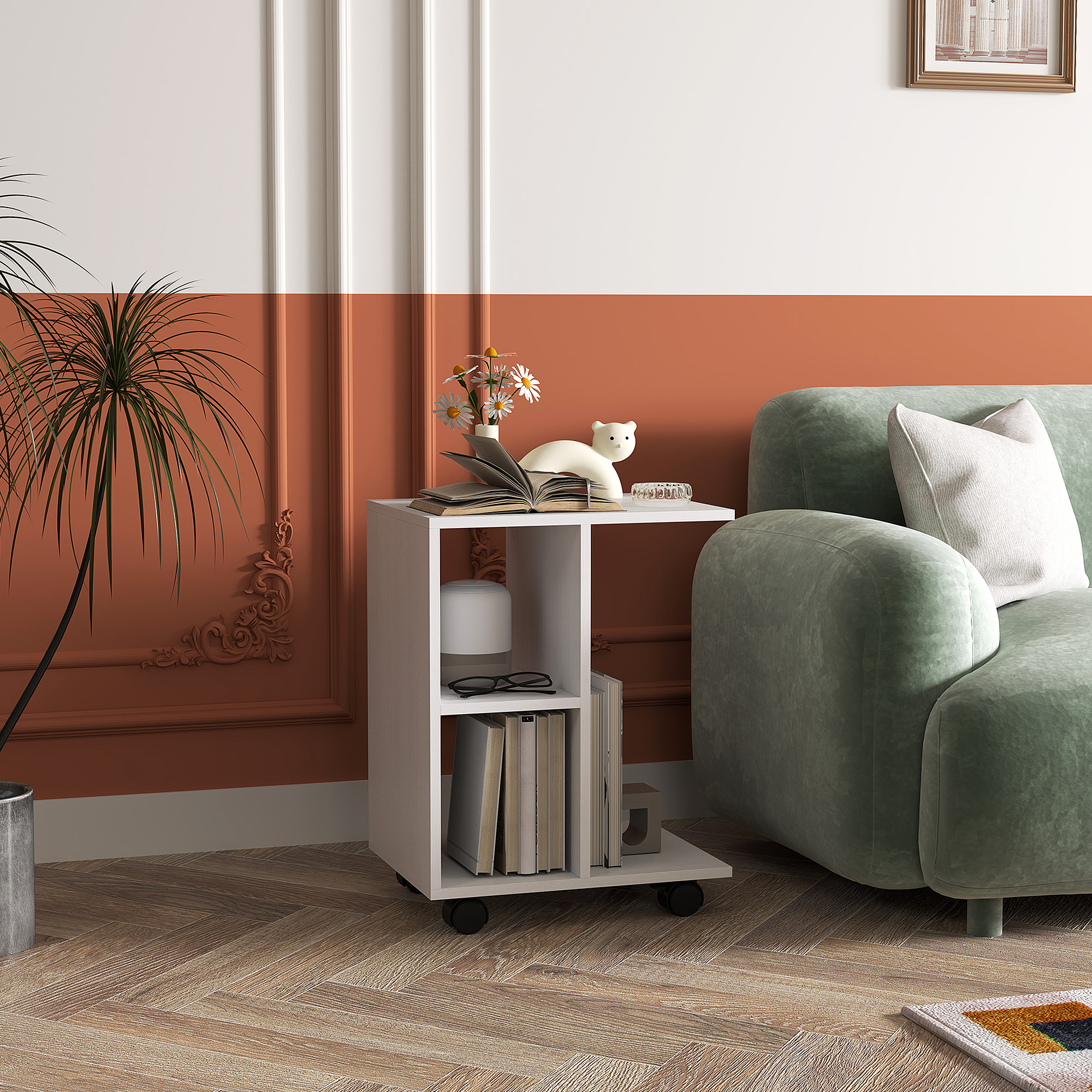 Weißer Beistelltisch mit Deko neben grünem Sofa und Pflanze.