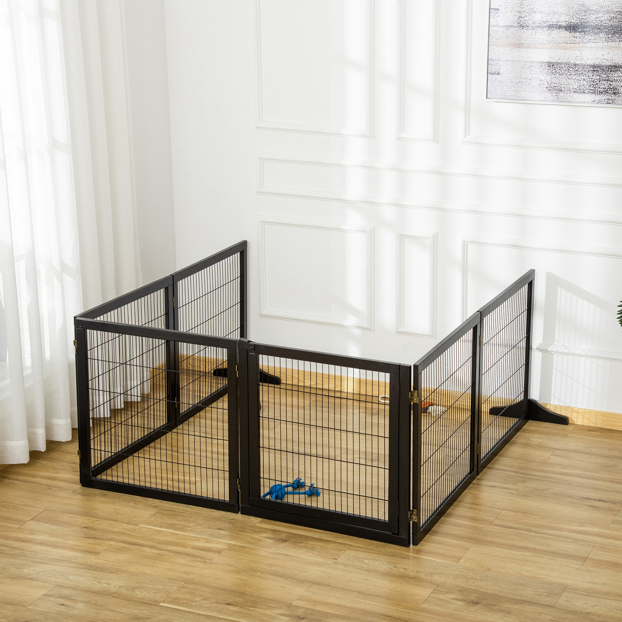 Ein schwarzer Hundeauslauf mit Metallgitter, auf einem Holzboden. Ein blaues Spielzeug liegt drin.