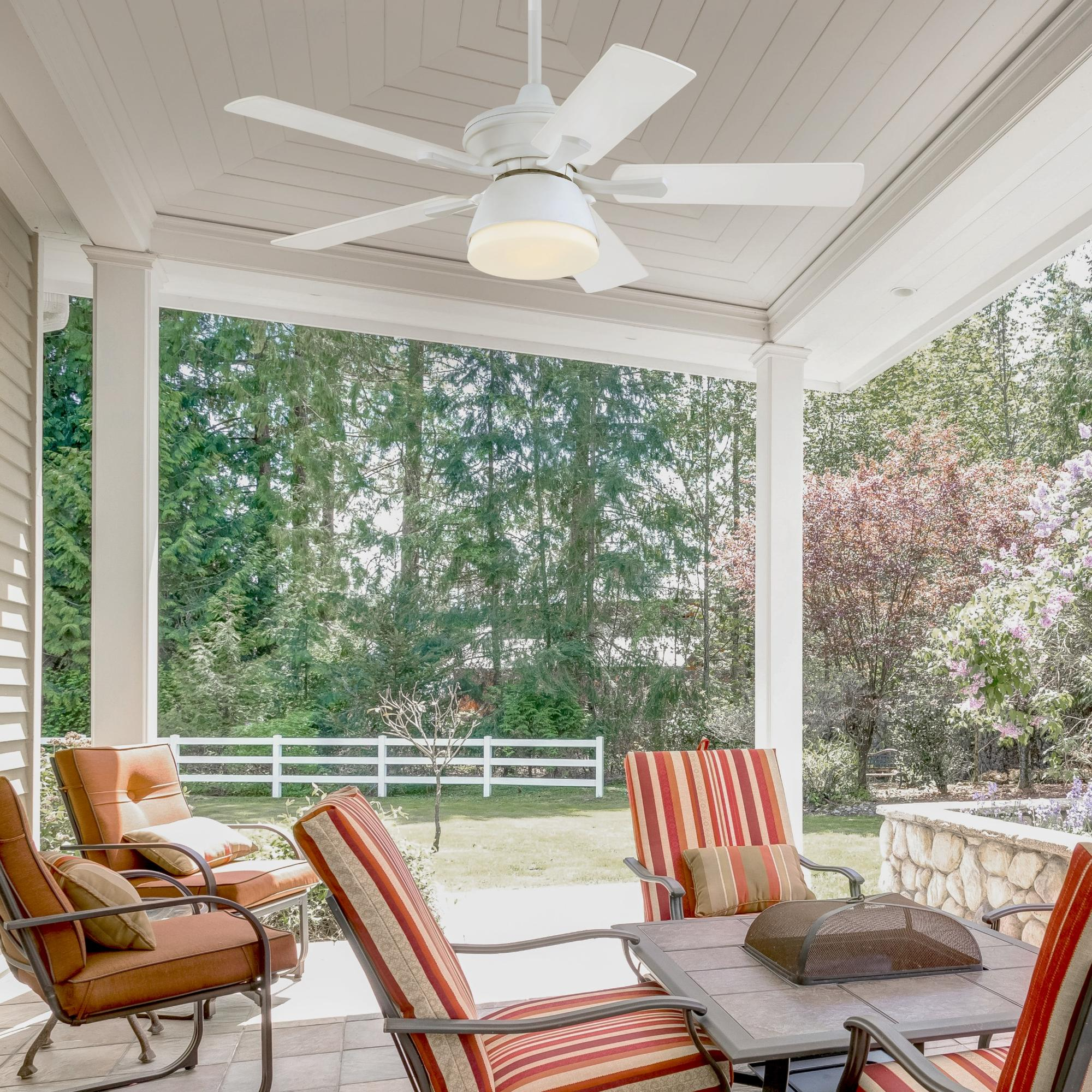 Eine Terrasse mit Stühlen, einem Tisch und einem weißen Deckenventilator mit fünf Flügeln.