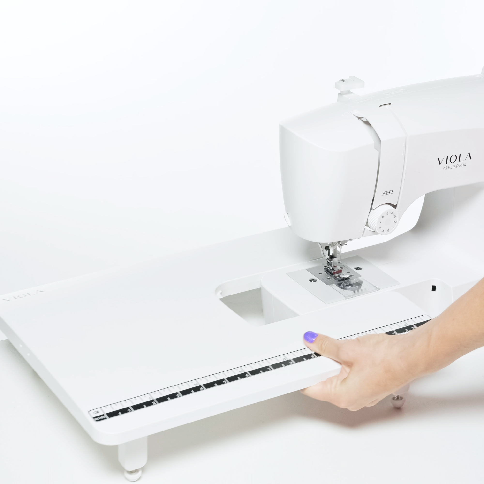 Nähmaschine mit Tischverlängerung. Eine Hand platziert die Verlängerung in die Maschine.