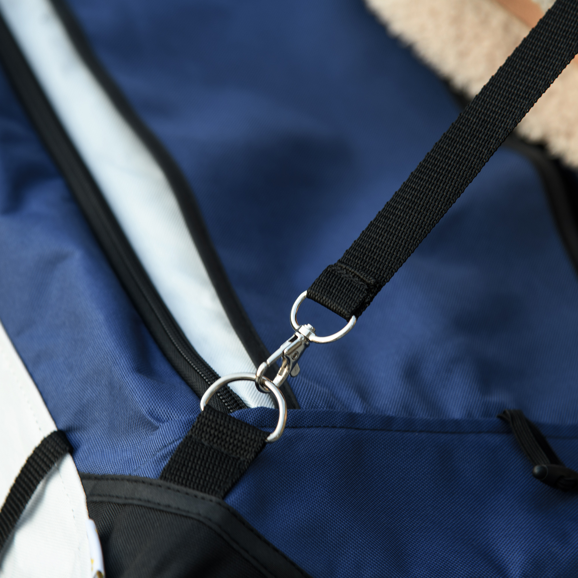 Nahaufnahme einer blau-weißen Tasche mit schwarzem Riemen und Metallverschluss.