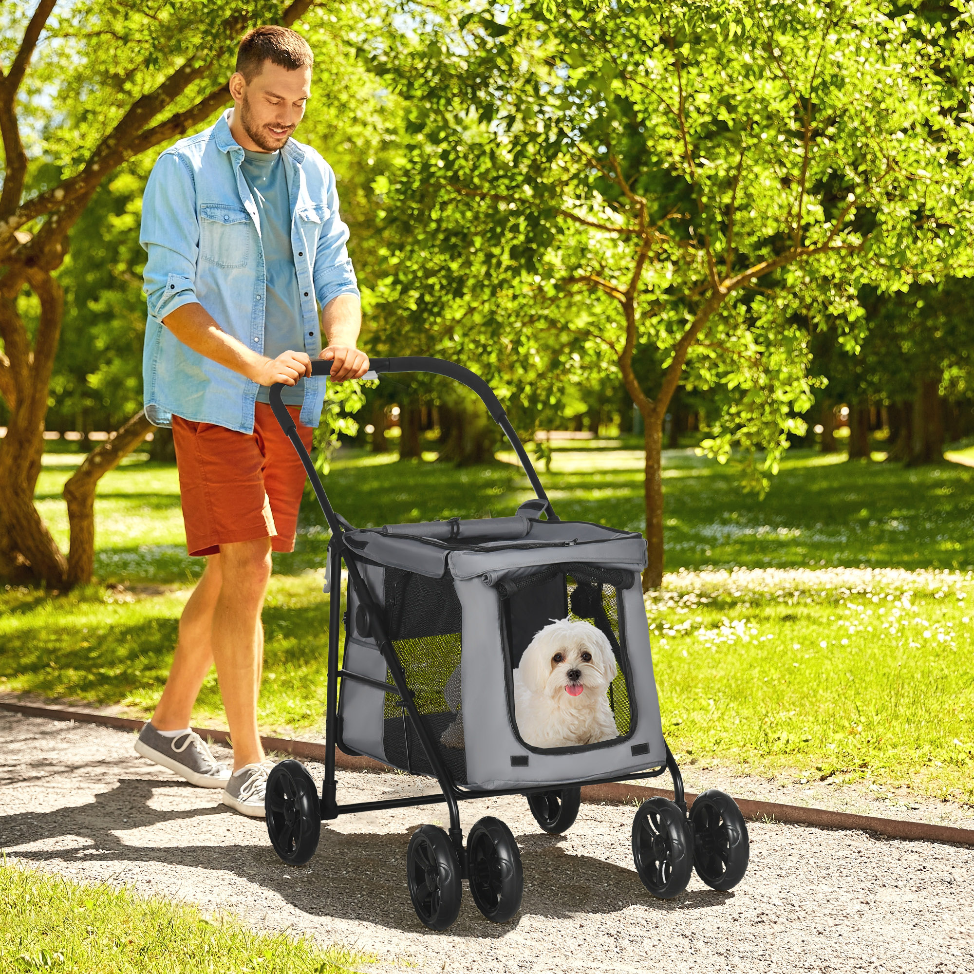 Ein Mann geht mit einem Tierkinderwagen in einem Park spazieren. Ein weißer Hund ist im Kinderwagen.