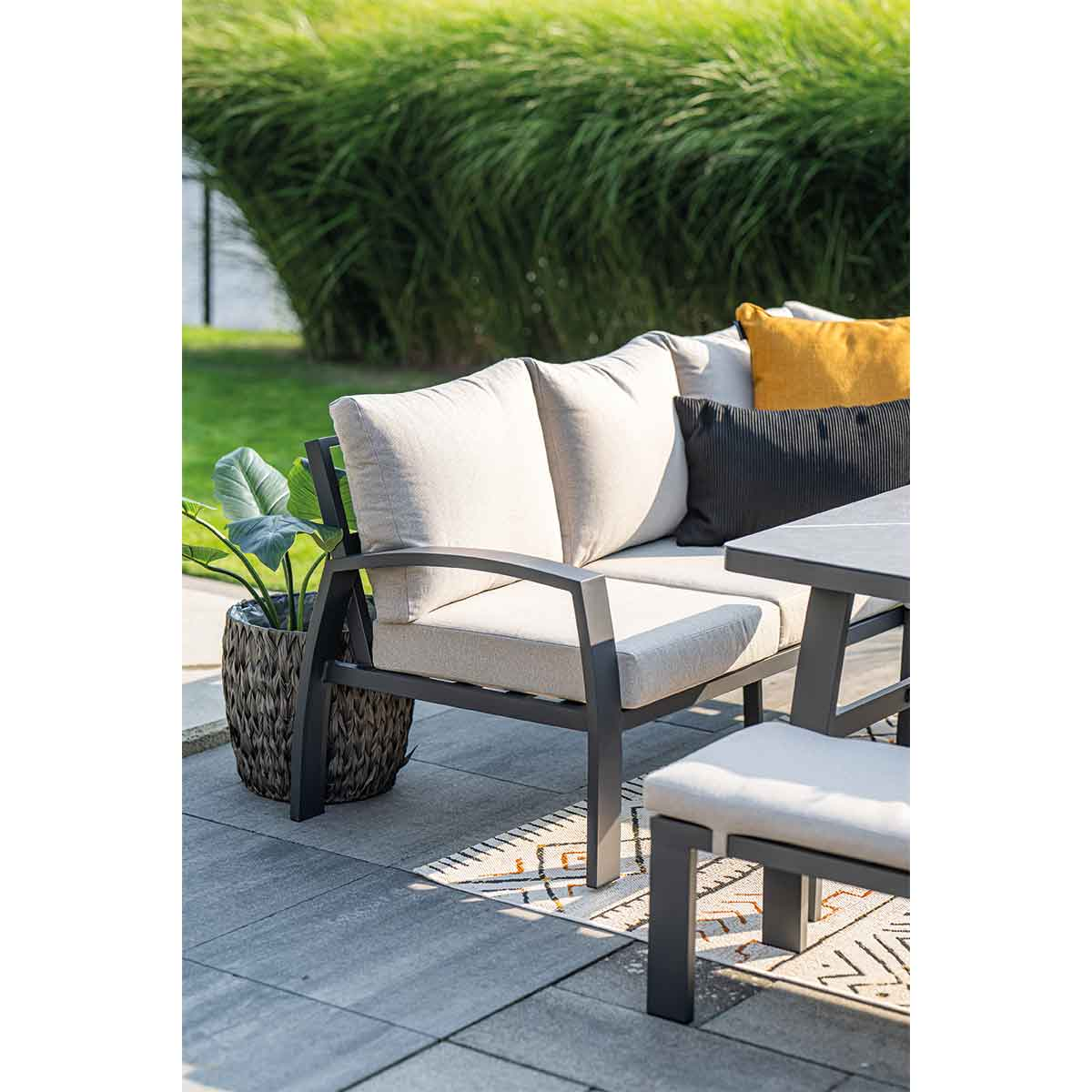 Scène extérieure avec mobilier de patio, comprenant un canapé, un banc, une table et une plante en pot.