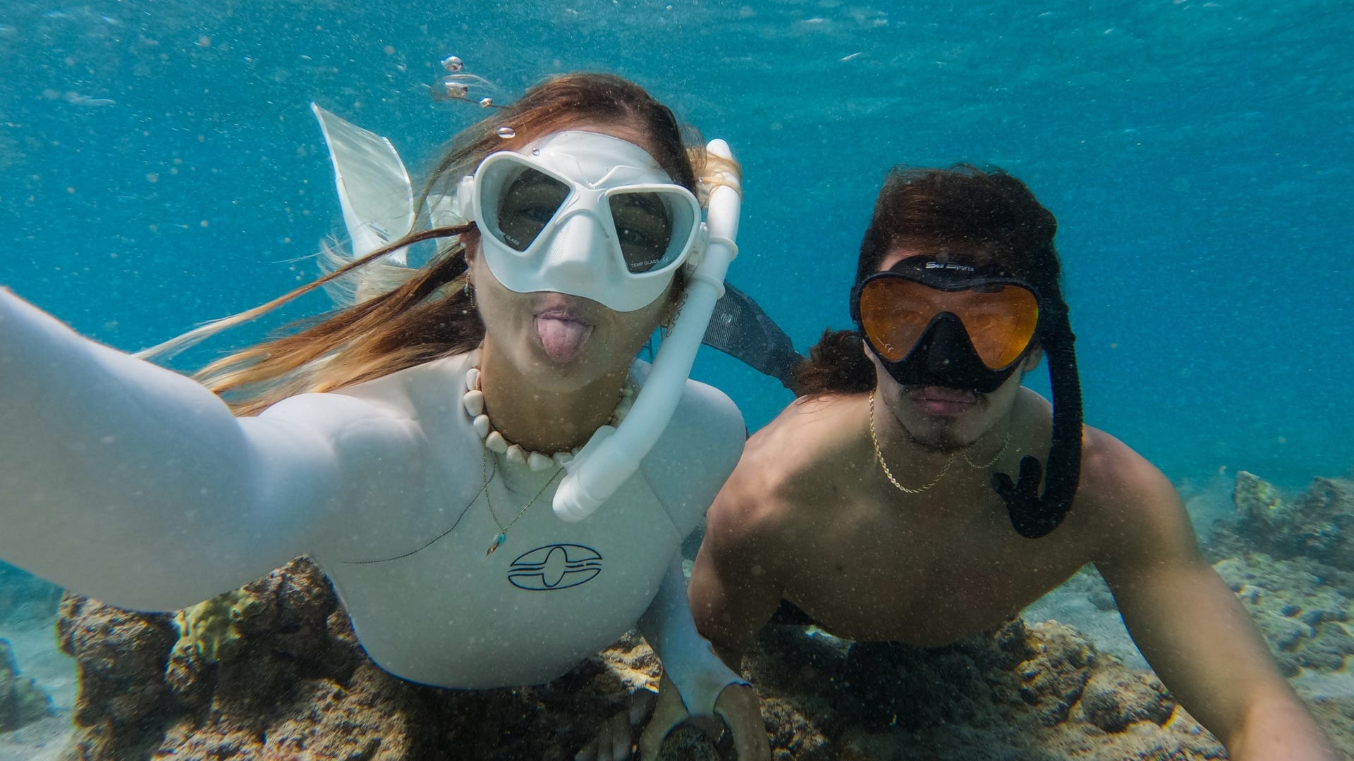 Dwie osoby pod wodą w sprzęcie do nurkowania, robiące selfie, uśmiechnięte.