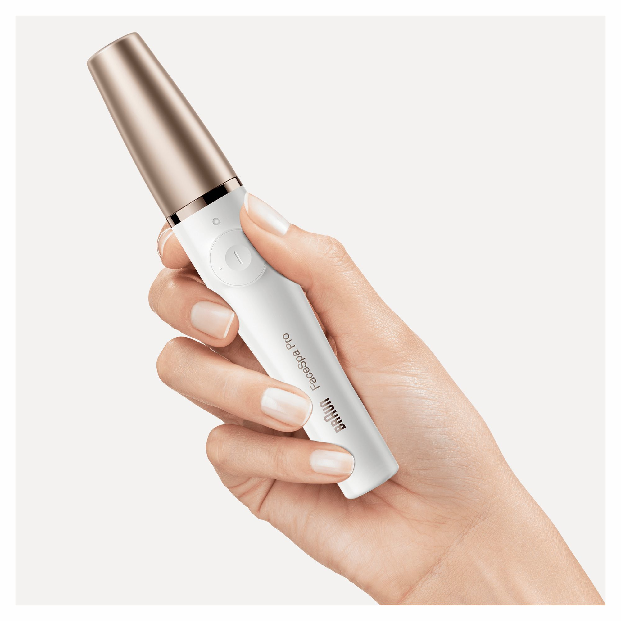 Die Hand einer Person, die ein weißes und goldenes Braun FaceSpa Pro hält. Weißer Hintergrund.