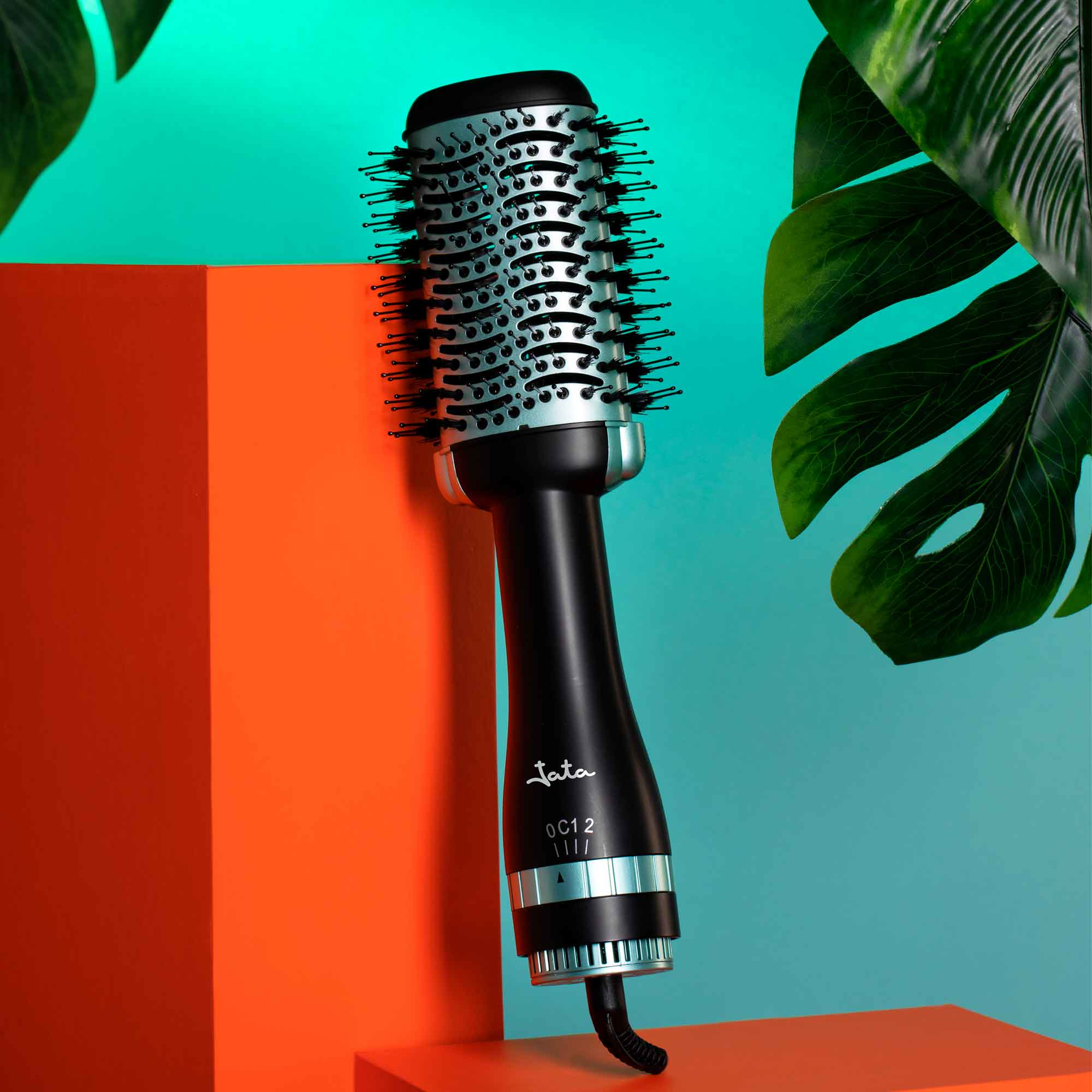 Czarna i srebrna suszarka do włosów z okrągłą szczotką, na tle miętowo-pomarańczowym.