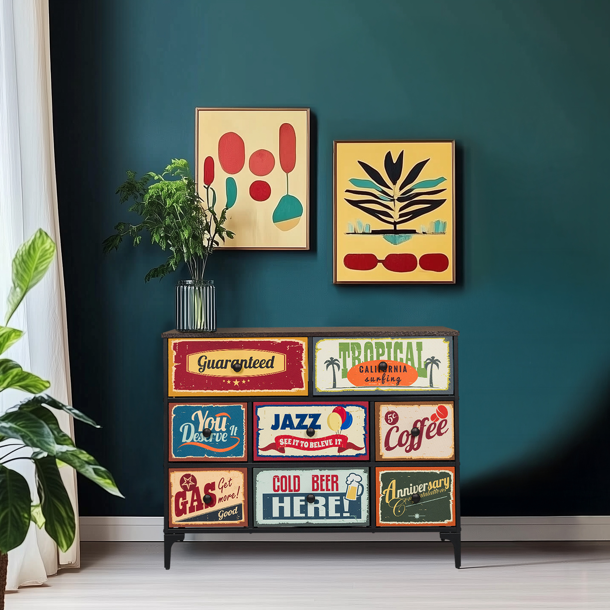Ein Schrank mit Vintage-Schildern auf den Schubladen, zwei gerahmte Kunstwerke und eine Pflanze an einer dunklen Wand.