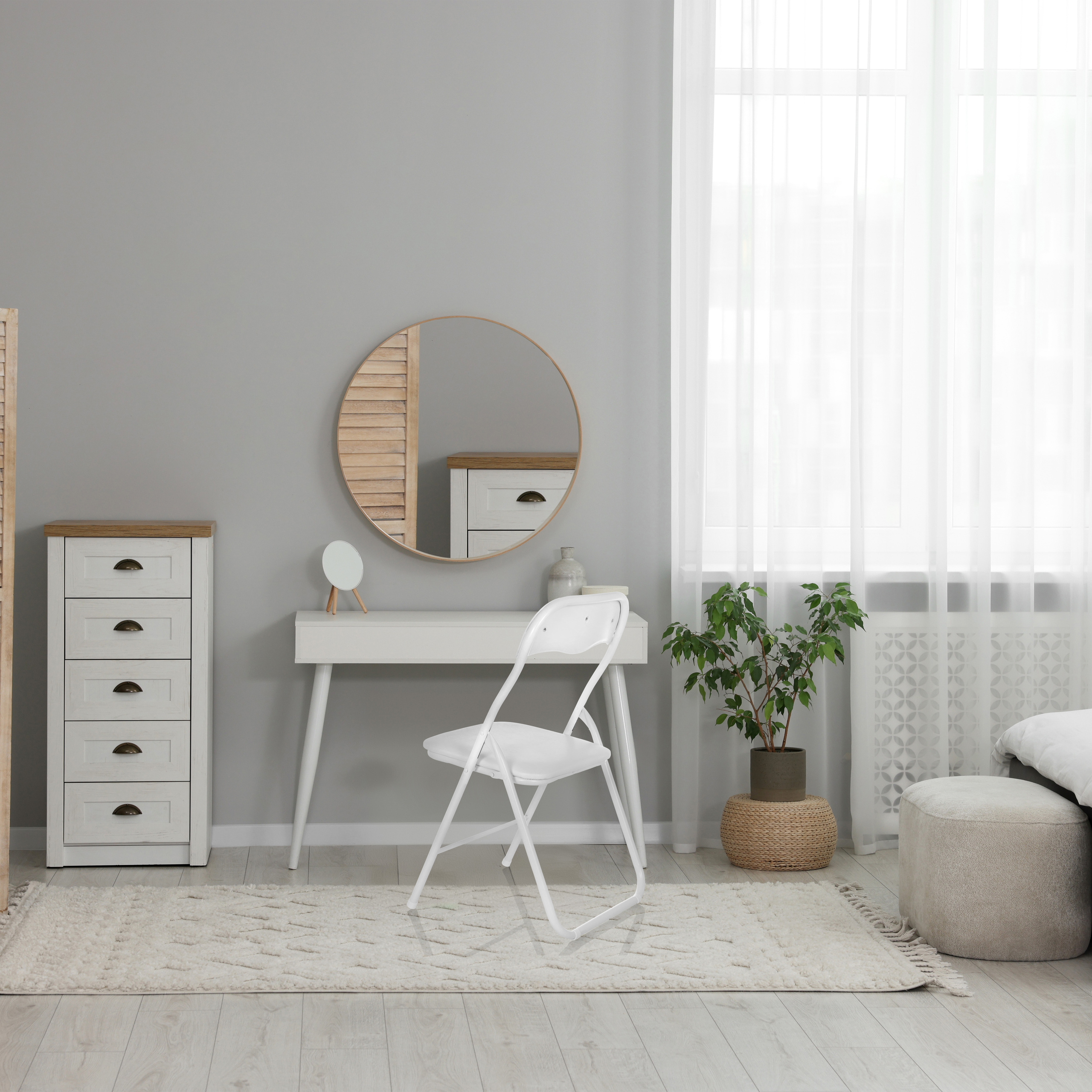 Ein Schlafzimmer mit weißem Schreibtisch, Stuhl, Spiegel, Schrank, Teppich und Fenster mit Vorhang.