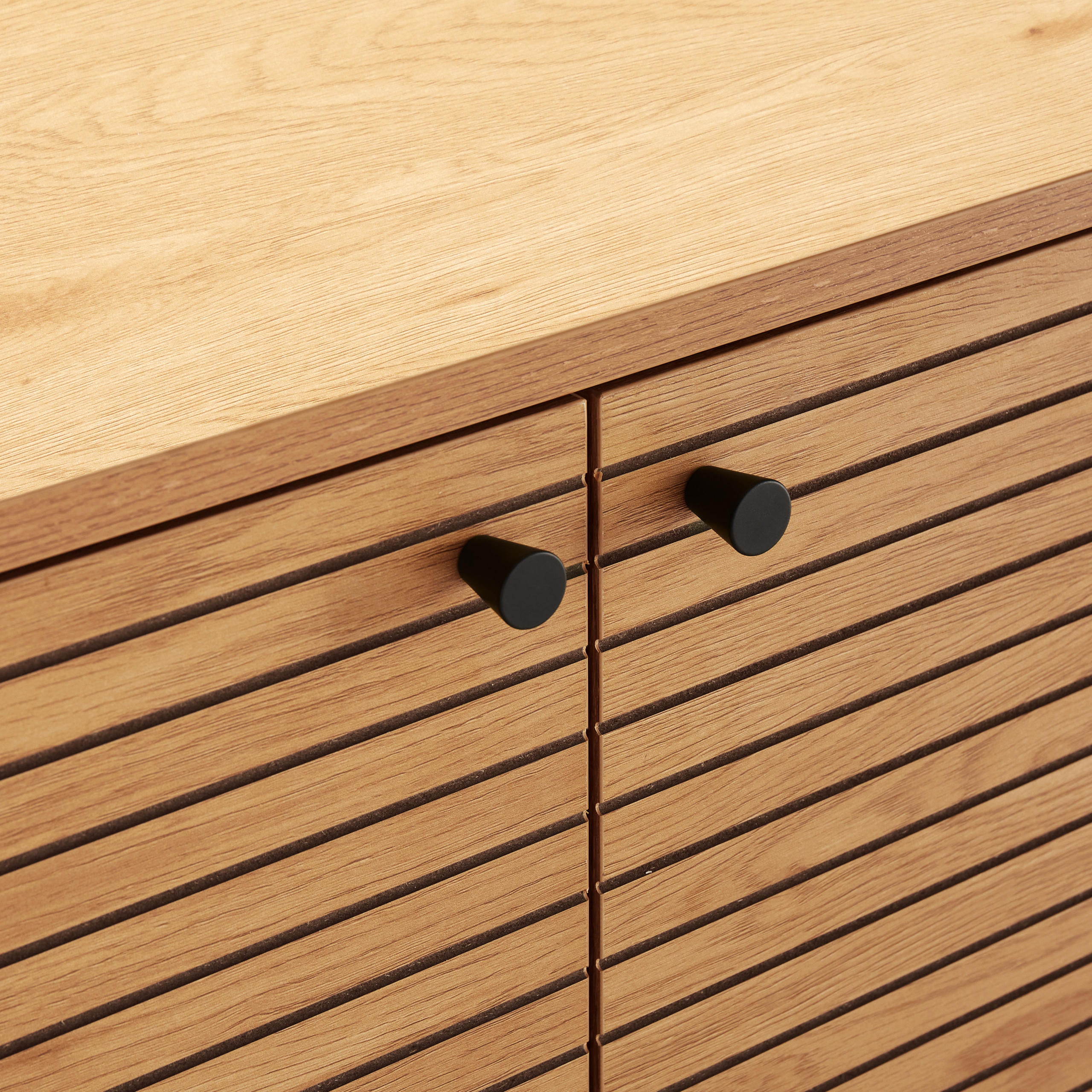 Nahaufnahme eines Holzschranks mit zwei schwarzen Griffen. Der Schrank hat horizontale Linien.