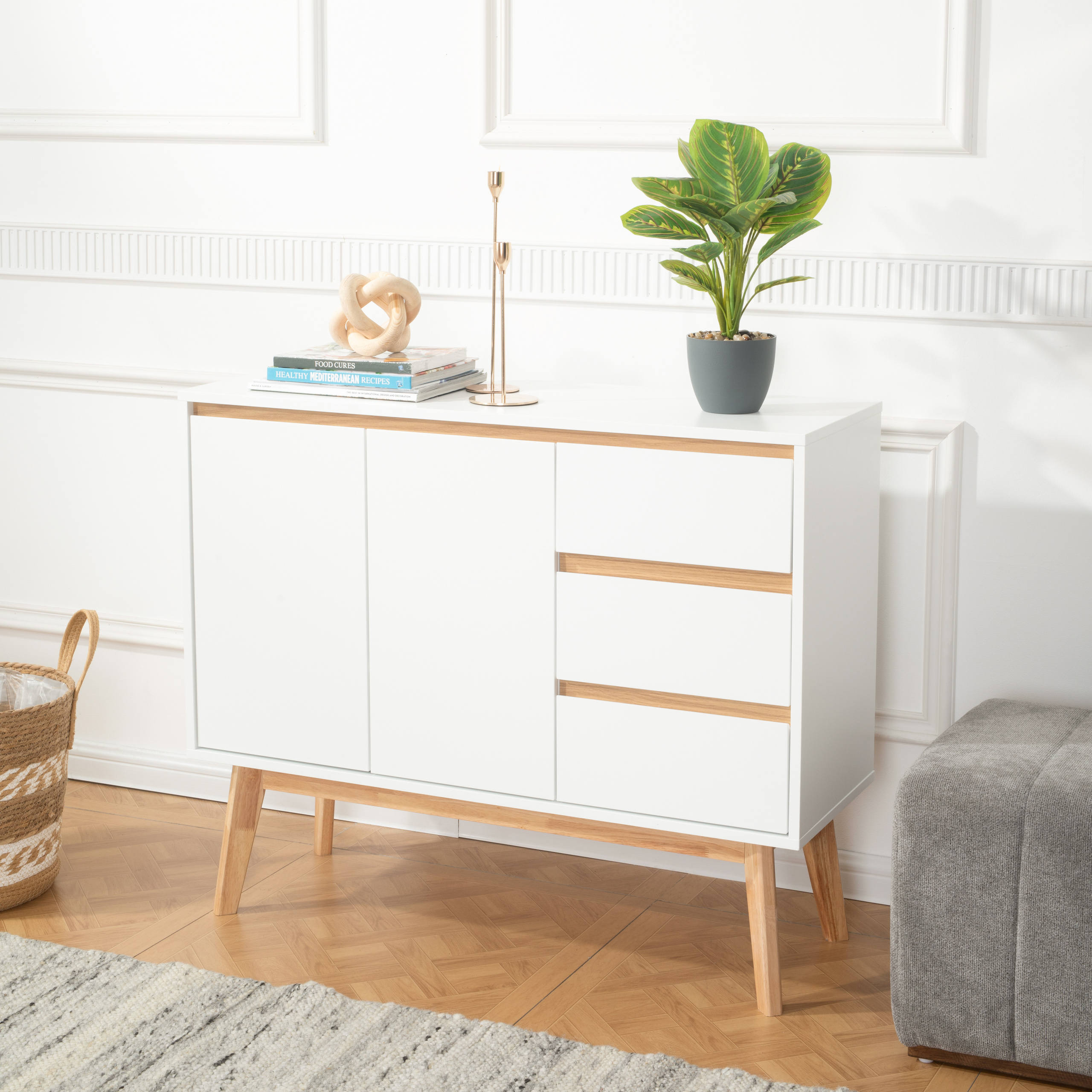 Weißes und braunes Sideboard mit grüner Pflanze, auf braunem Parkettboden.