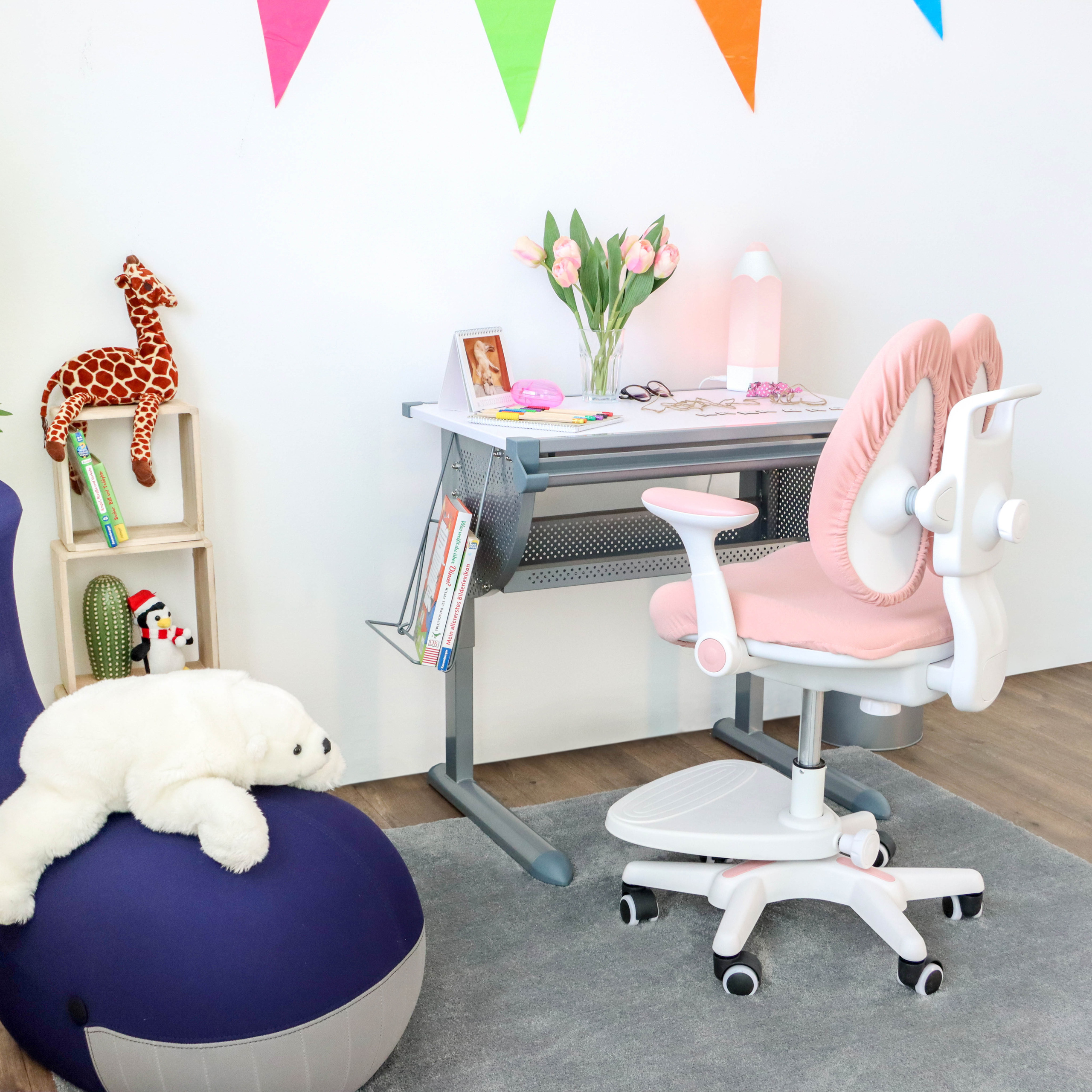 Kinderschreibtisch mit rosa Stuhl und Spielzeug auf dem Boden.