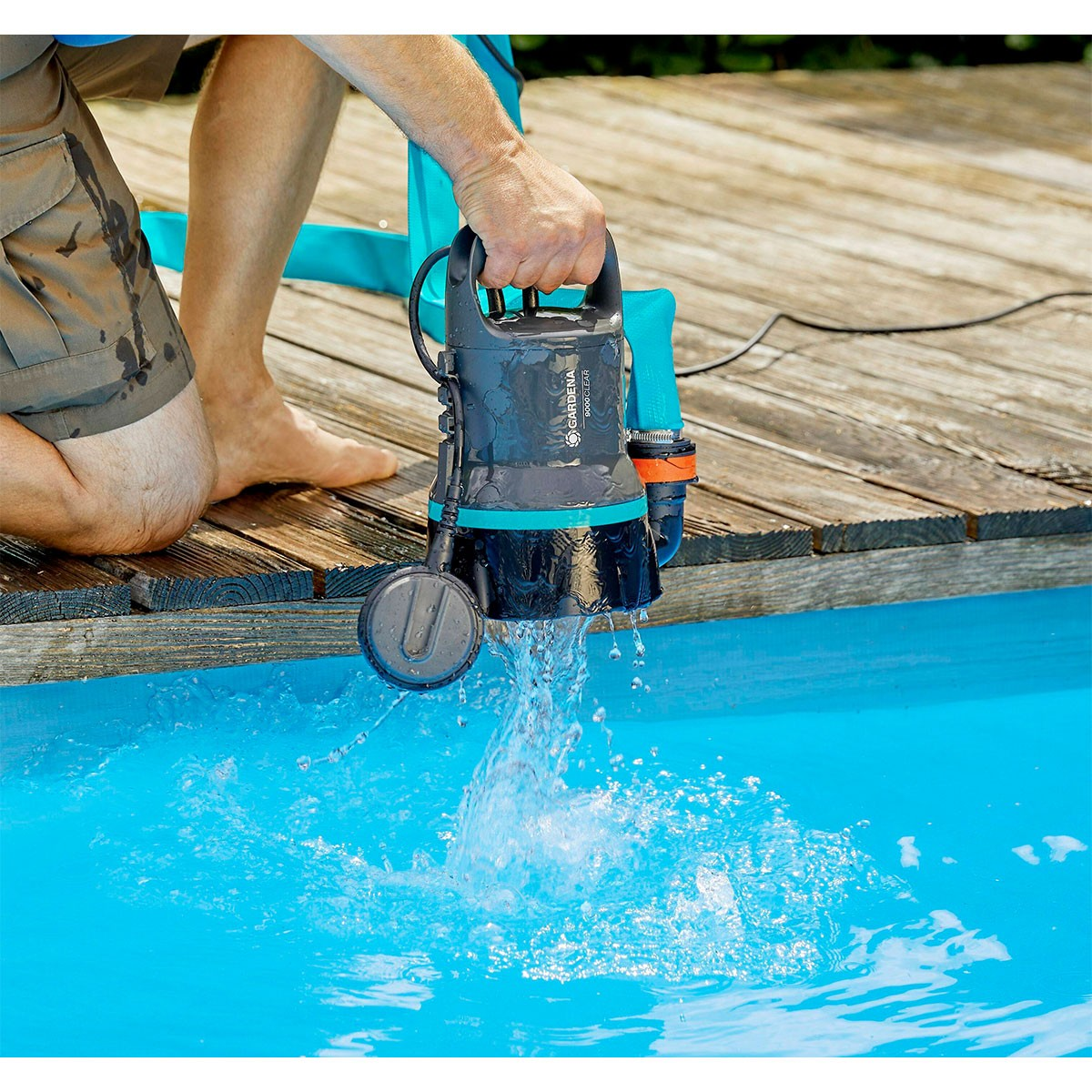 Un uomo tiene in mano una pompa nell'acqua. L'acqua schizza dalla pompa.