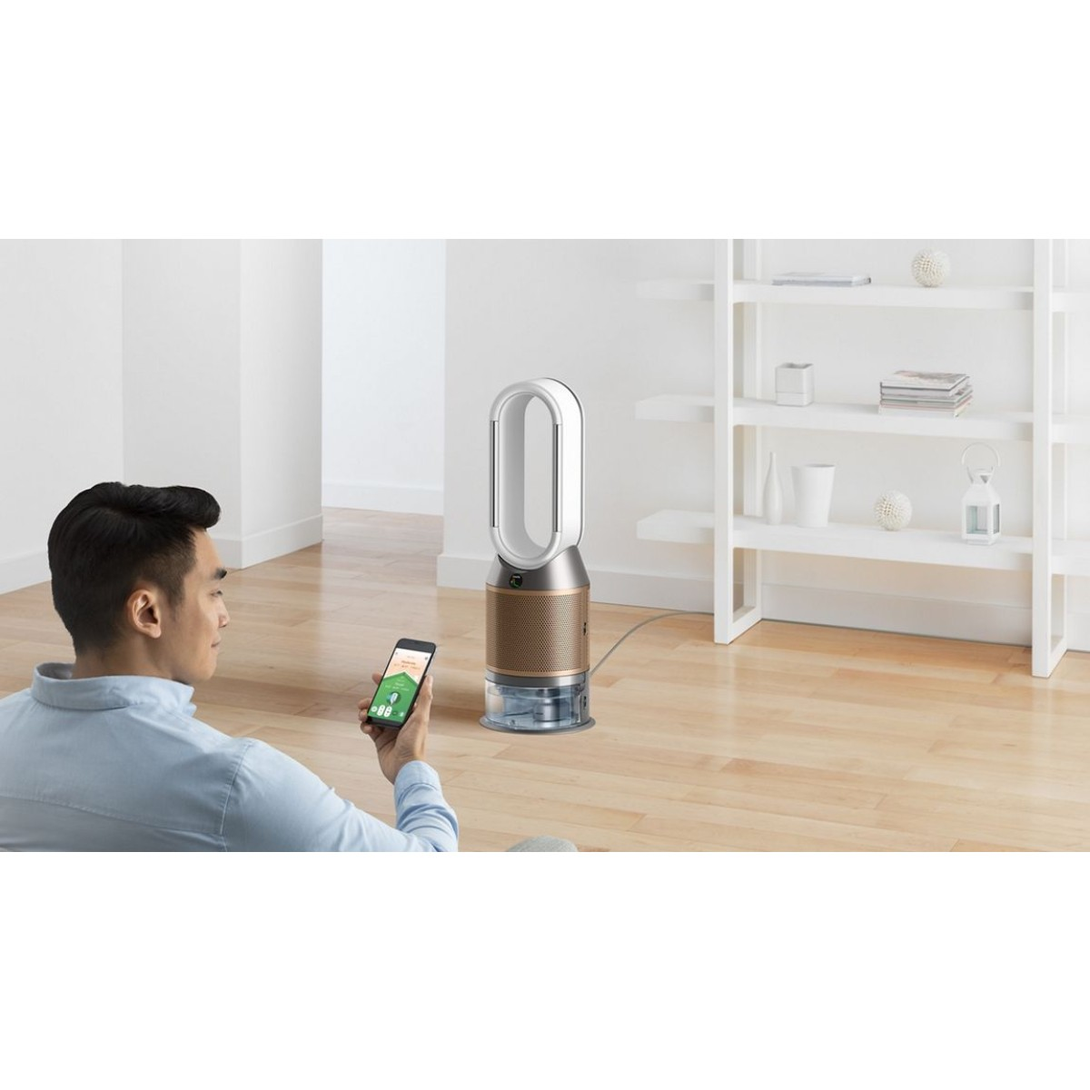 Man die een smartphone gebruikt om een witte en gouden ventilator te bedienen, met een plank op de achtergrond.