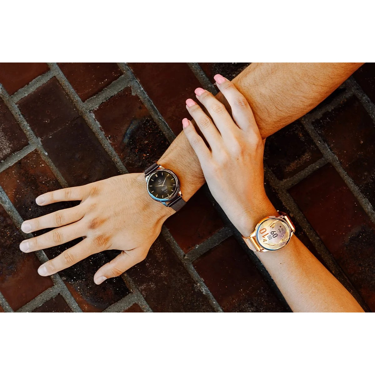 Primo piano di due polsi, ognuno con un orologio. Uno è argento, l'altro oro, con unghie rosa.