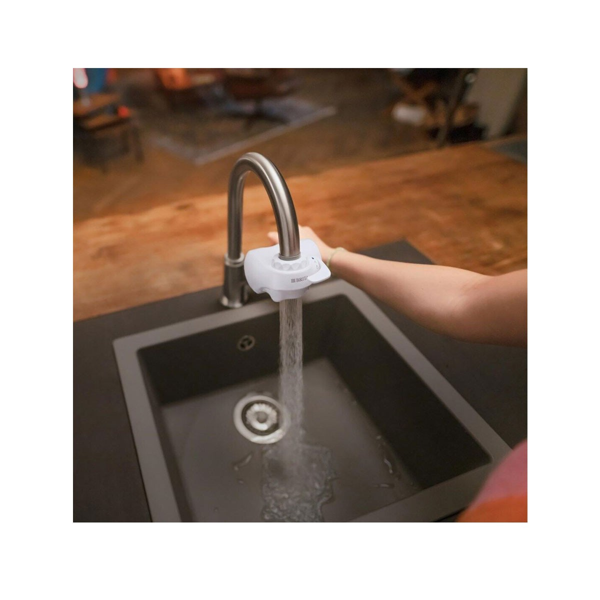 Sistema di filtraggio dell'acqua collegato a un rubinetto, con acqua che scorre in un lavandino.
