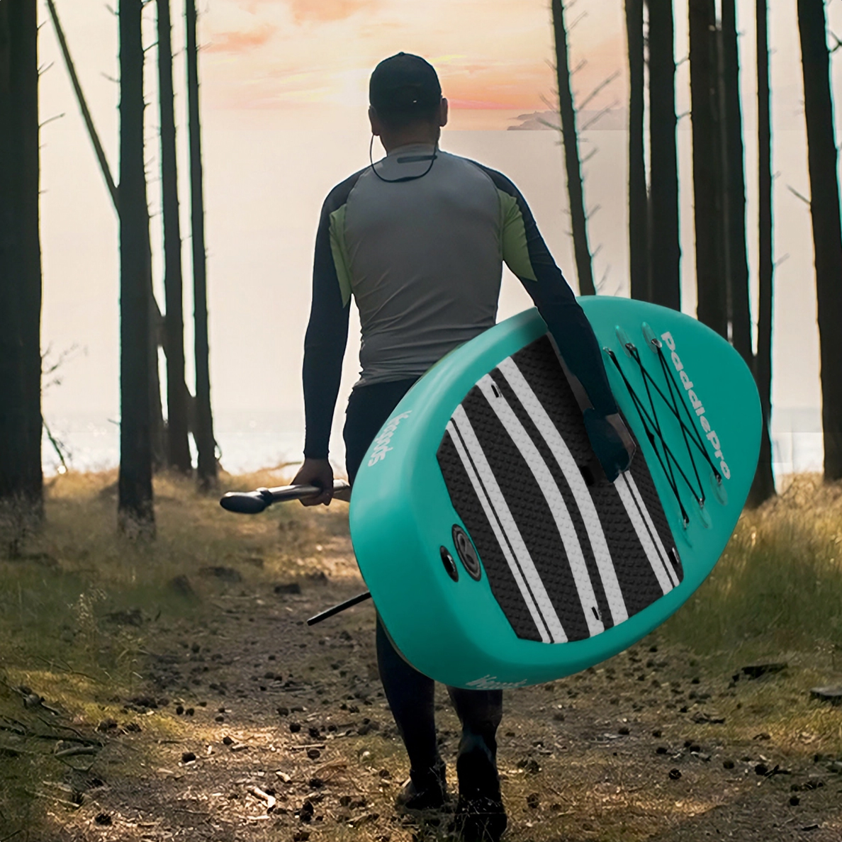 Persoon die wegloopt, met een teal paddleboard en peddel, in een bos.