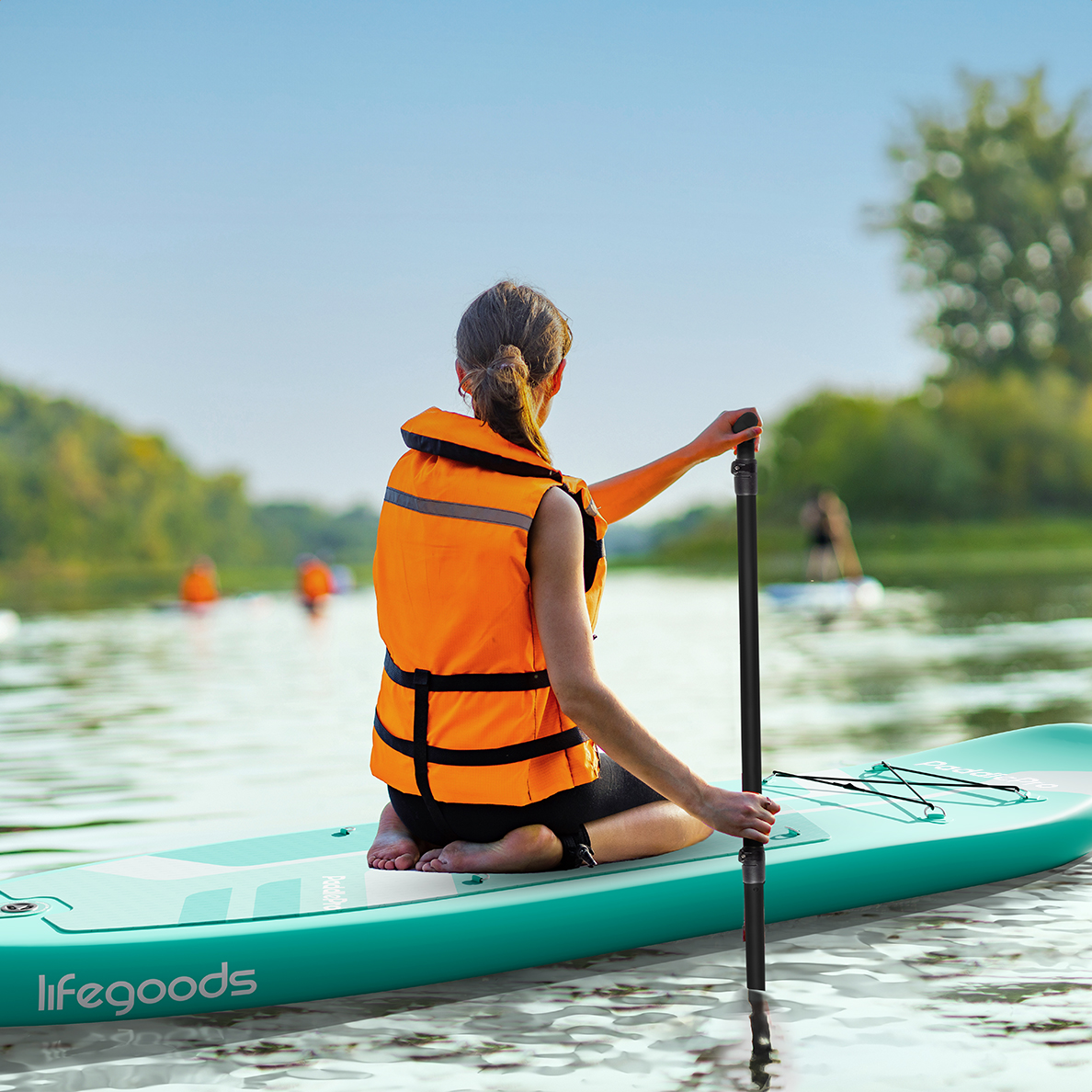 Vrouw op een teal paddleboard op het water, met een reddingsvest, peddelend.