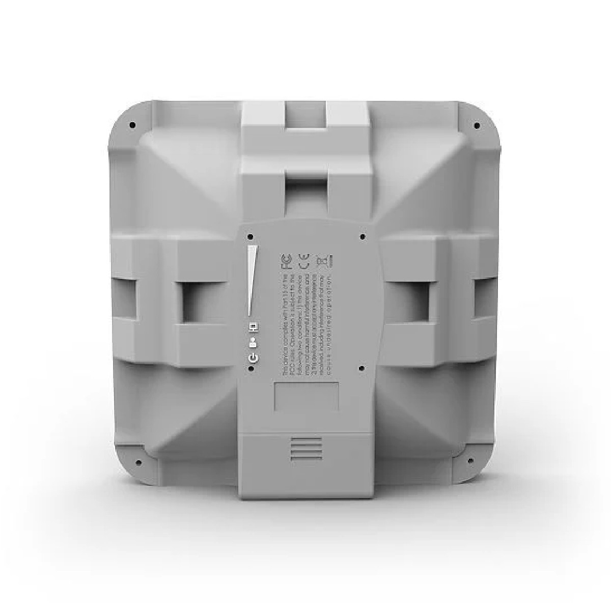 Tył szarego kwadratowego urządzenia z różnymi portami, otworami wentylacyjnymi i małą etykietą informacyjną.