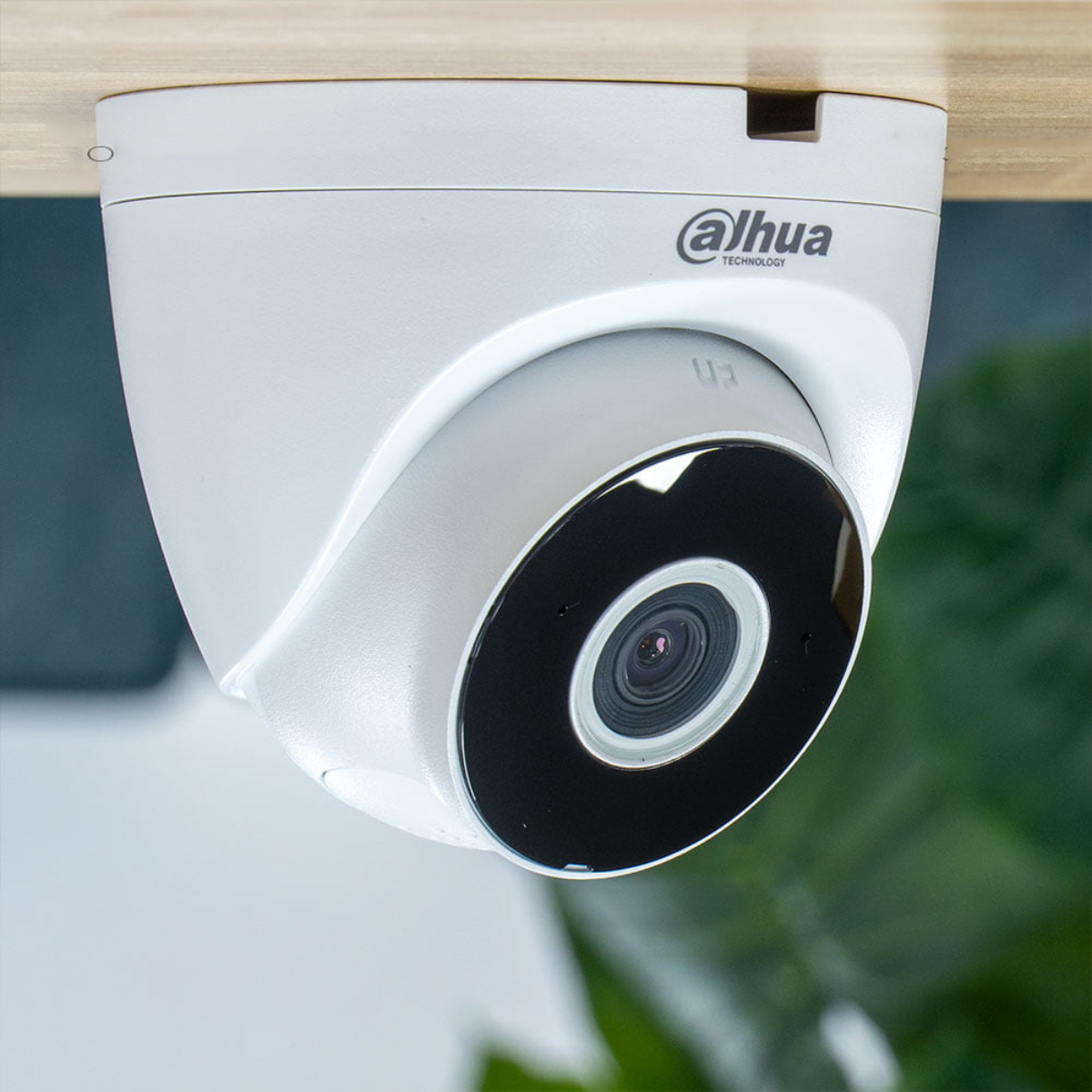 White Dahua security camera, black lens, mounted on a wooden surface.