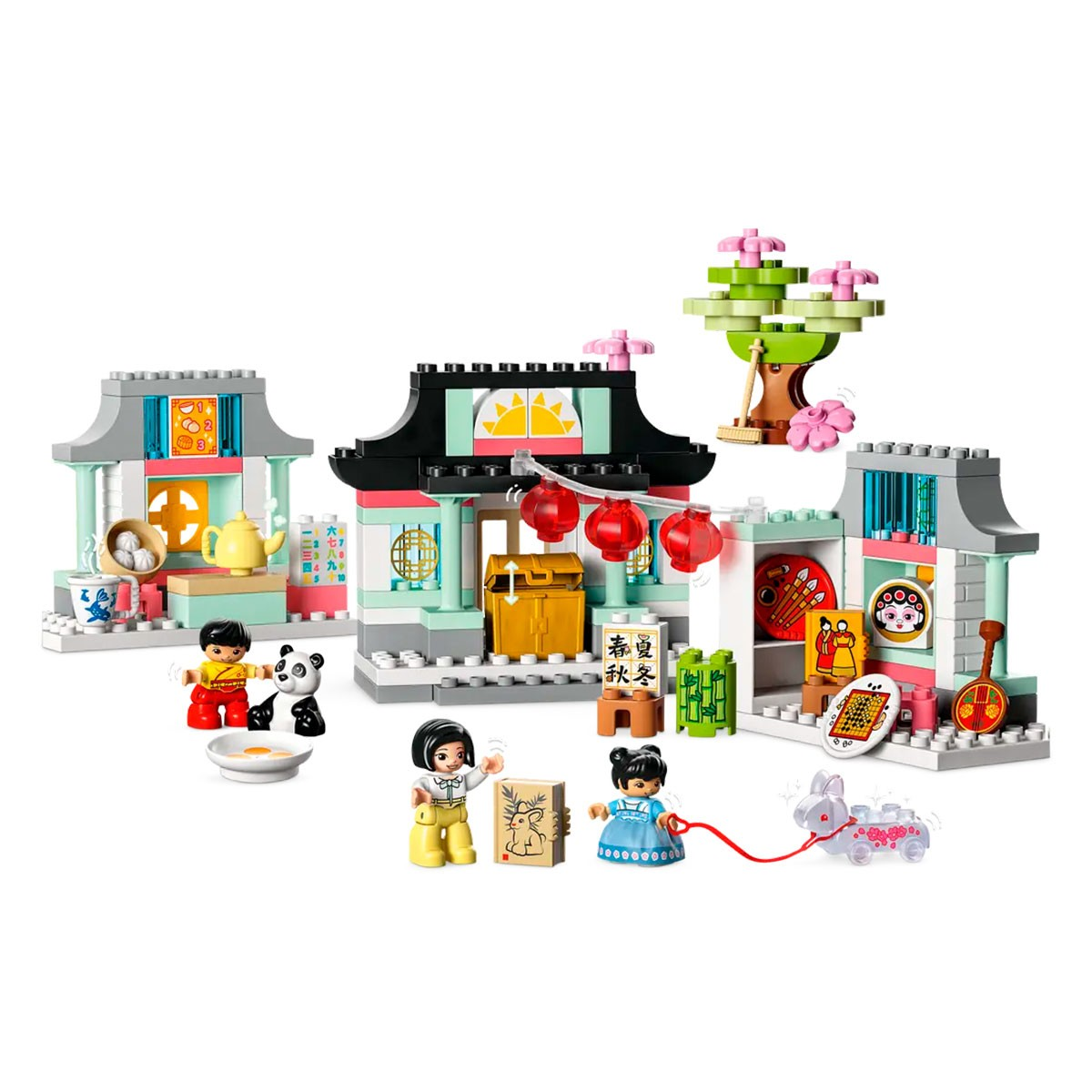 Un set Lego Duplo con edifici, personaggi e un albero, su una superficie bianca.