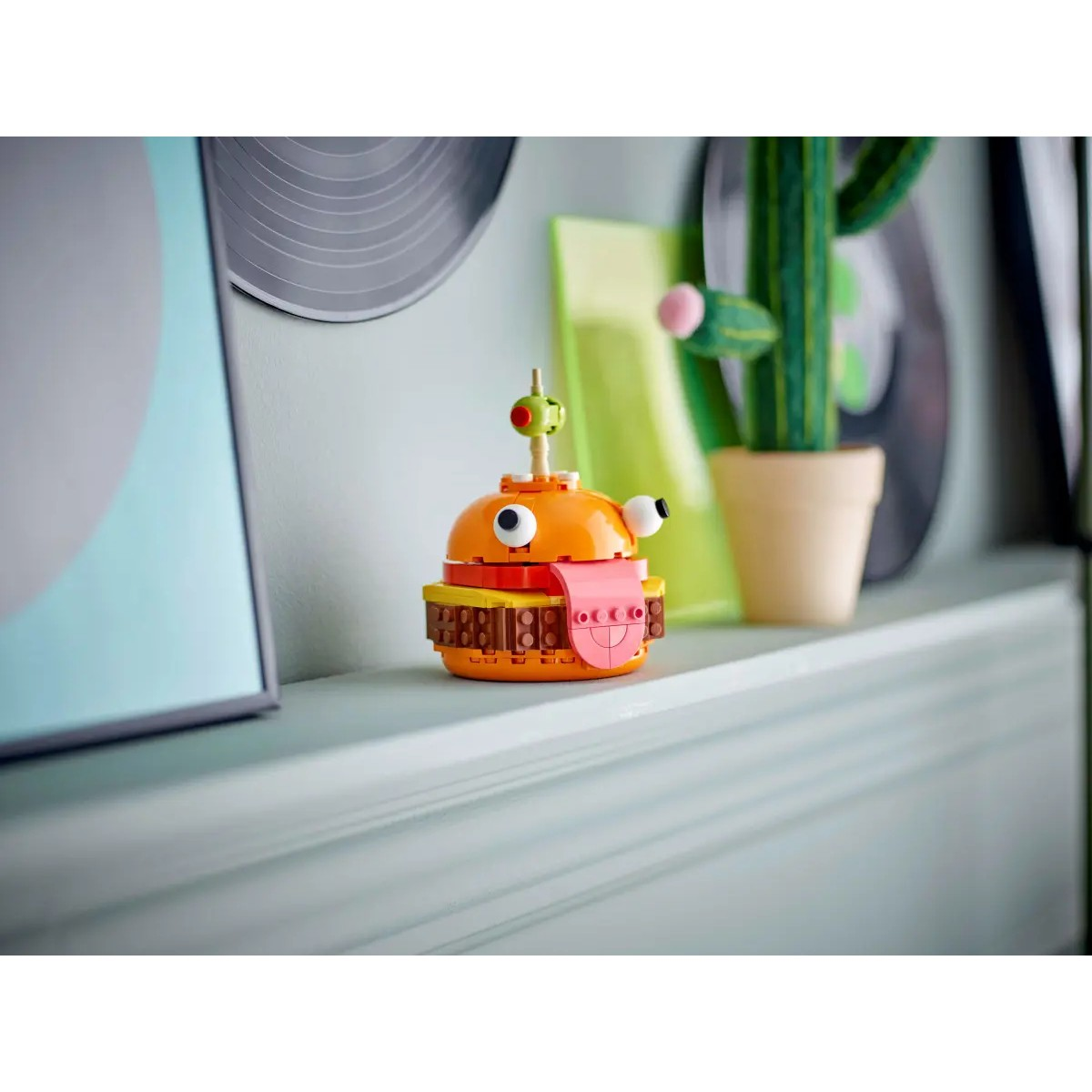 Lego-Burger-Modell auf einem Regal. Enthält einen Hintergrund mit anderen Objekten.