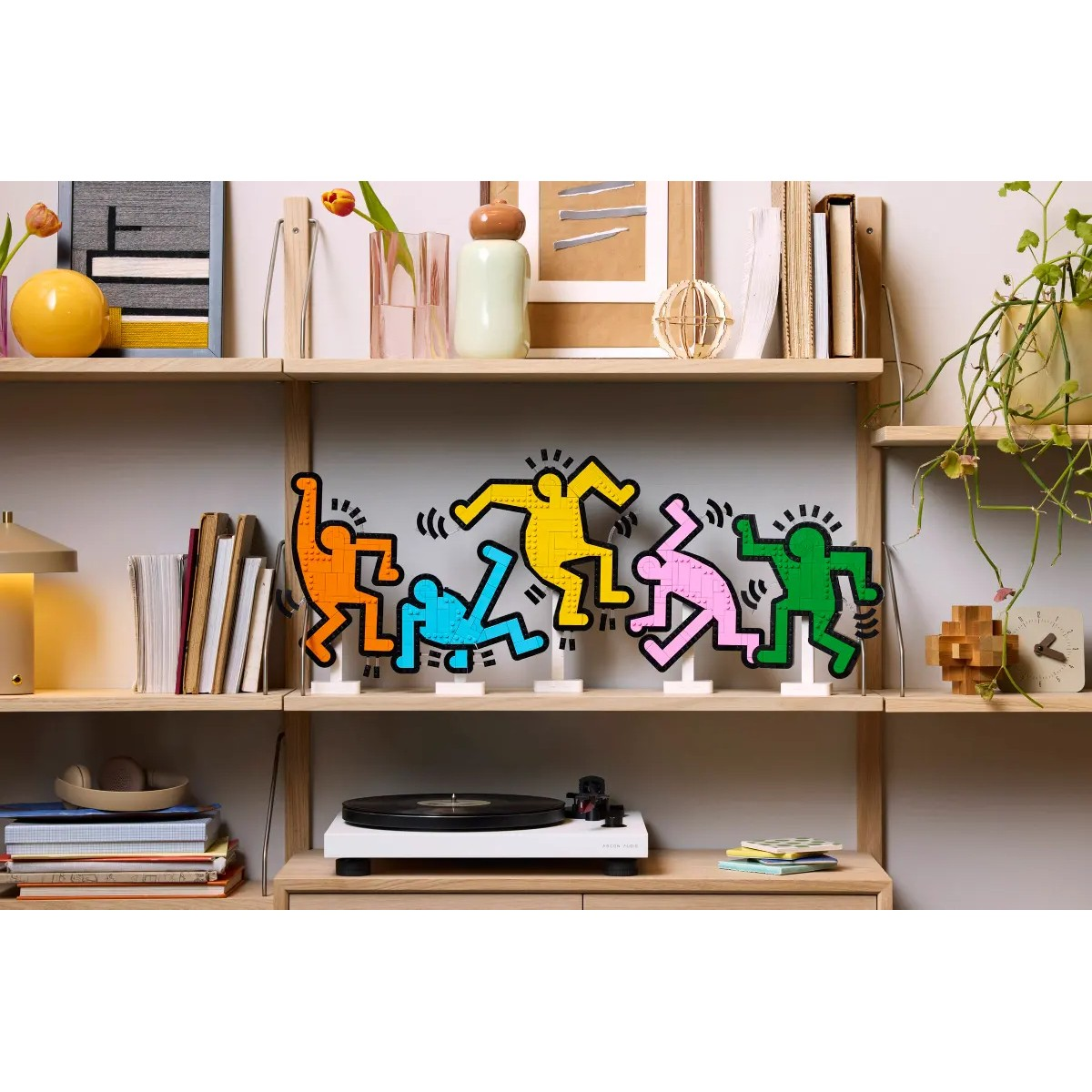 Sztuka LEGO: Kolorowe tańczące figury na półce nad gramofonem.