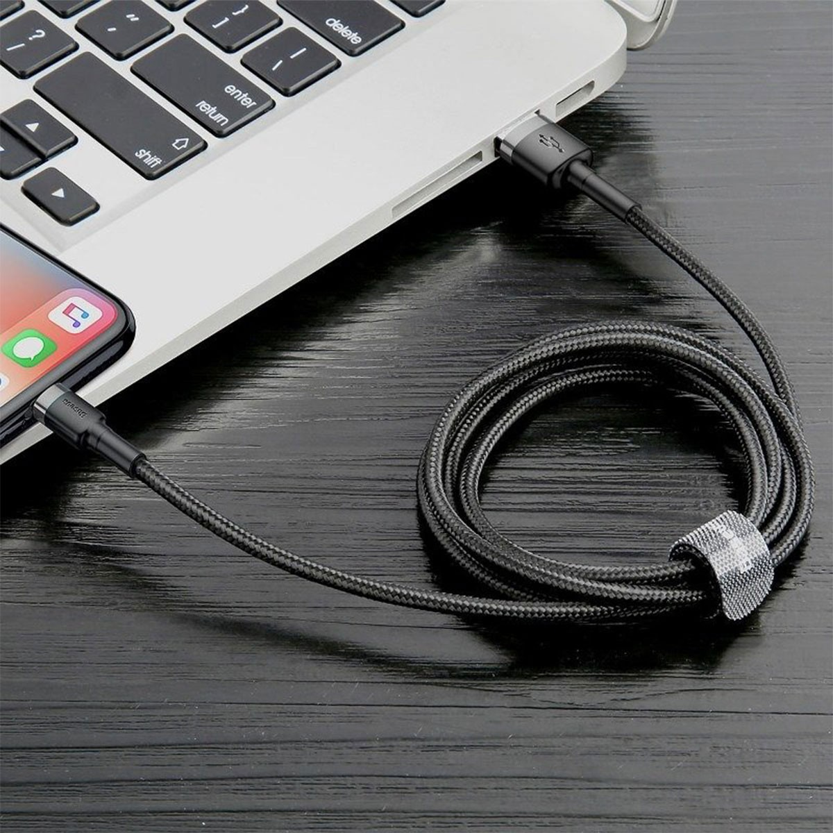 Smartfon podłączony do laptopa czarnym kablem USB.