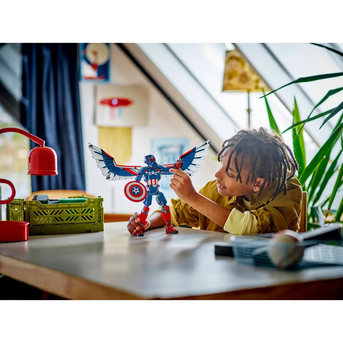Chłopiec bawi się zabawką Lego Kapitan Ameryka. W tle ozdobiony pokój.