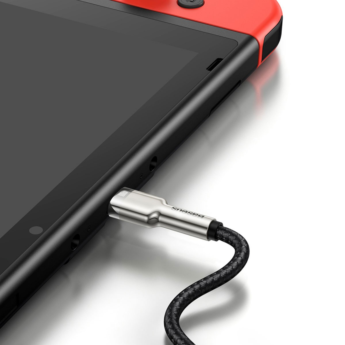 Kabel USB-C podłączony do czarnego urządzenia, obok czerwono-czarnej konsoli Switch.