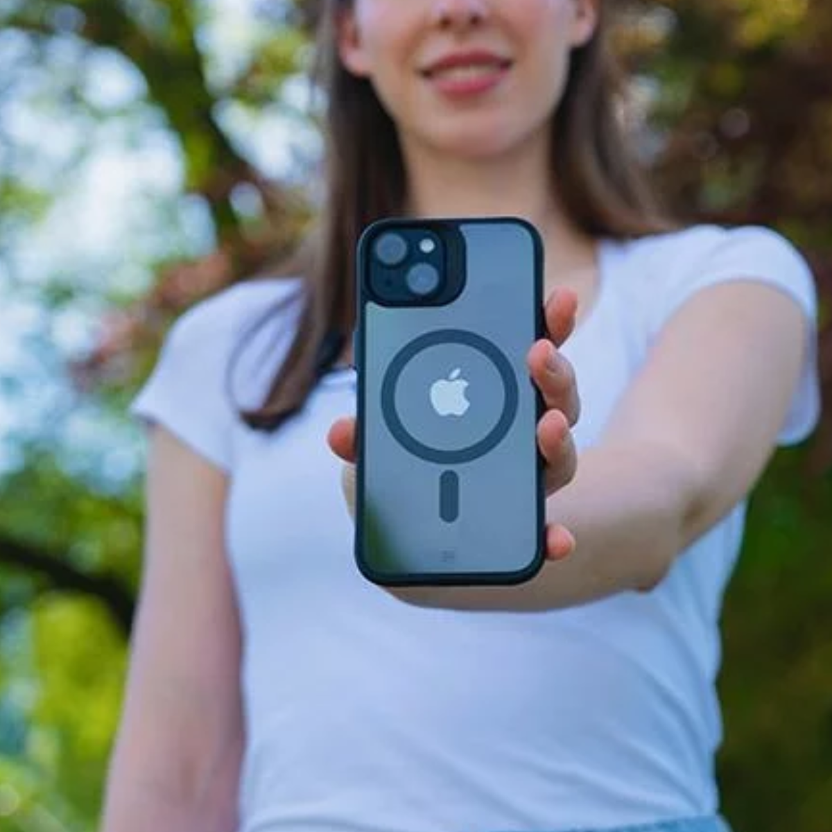 Donna che tiene un telefono con una custodia che mostra il logo Apple. La custodia è nera e trasparente.