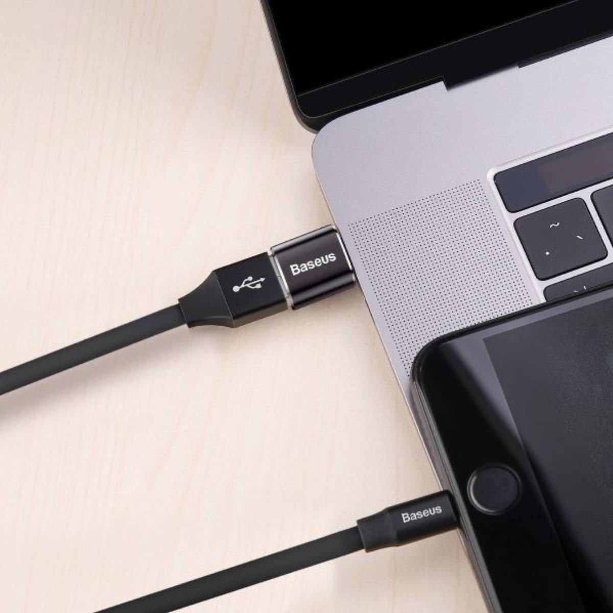Czarny kabel USB podłączony do laptopa i smartfona. Oba urządzenia są czarne.