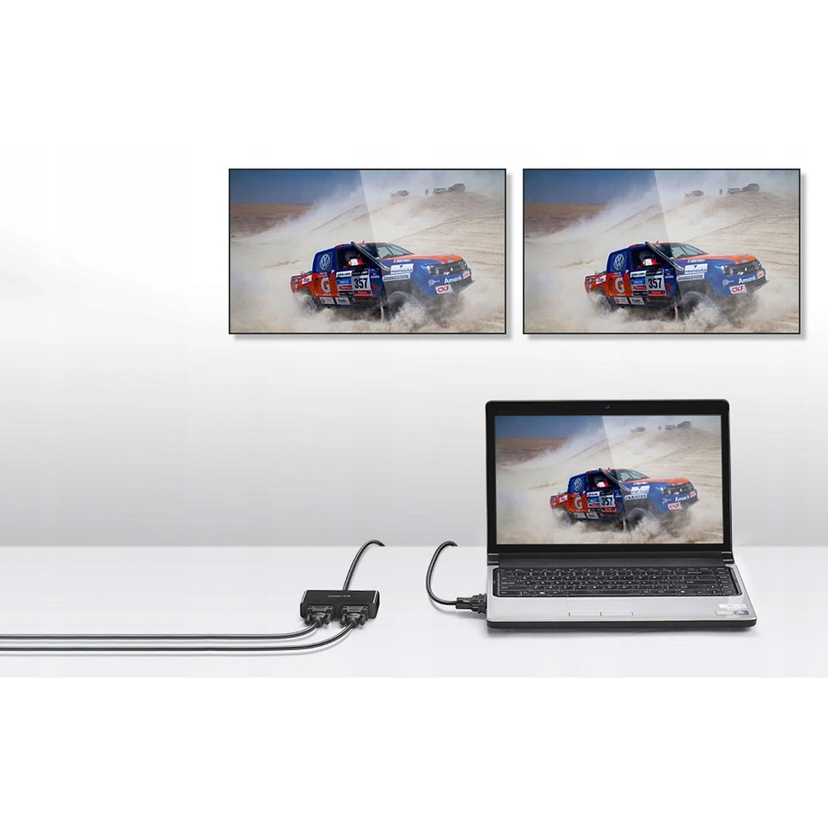 Dwa ekrany pokazują samochód rajdowy. Laptop wyświetla ten sam obraz. Czarny konektor po lewej.
