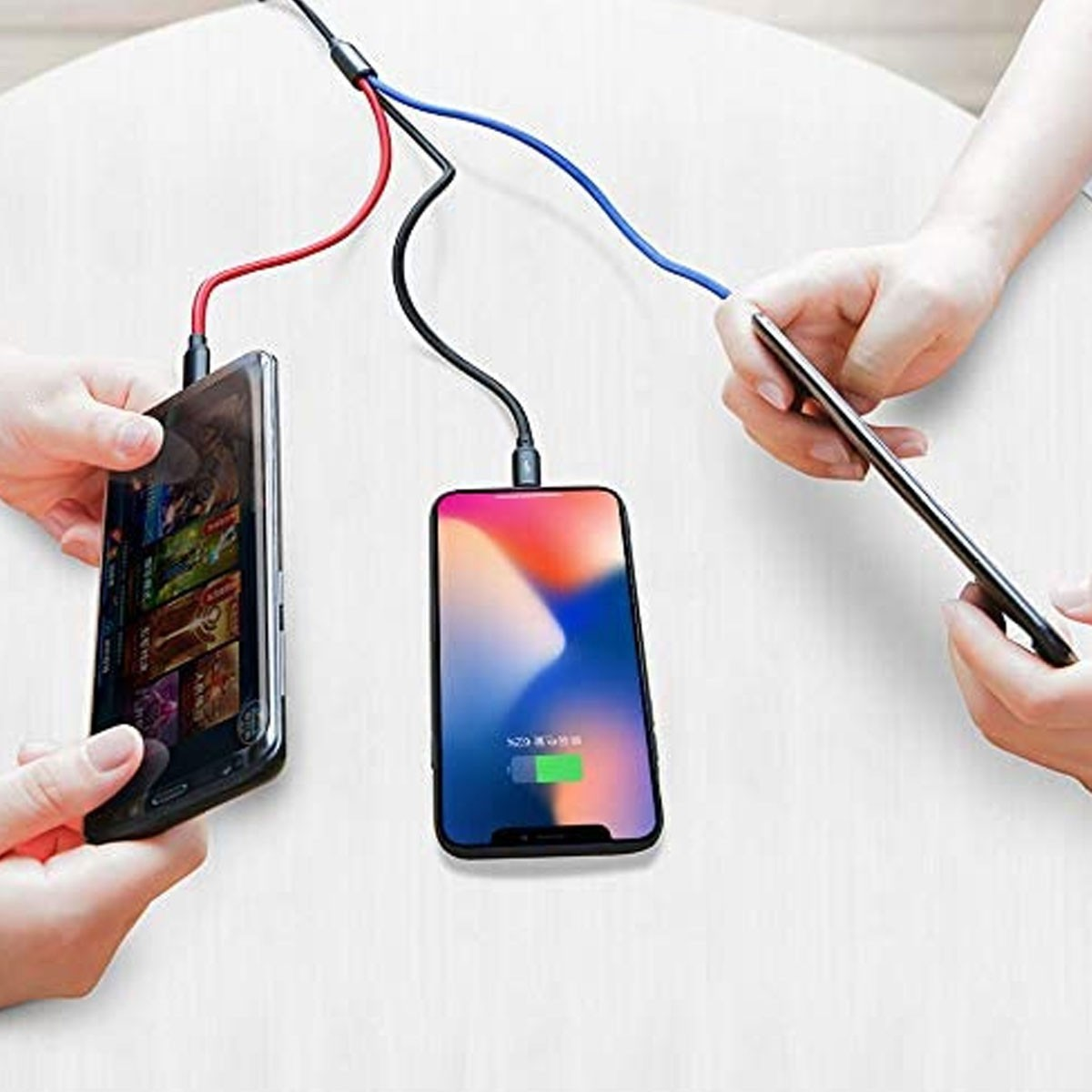 Dwa telefony ładujące się za pomocą trzech kabli. Jeden telefon jest czarny, drugi niebieski. Biała powierzchnia.