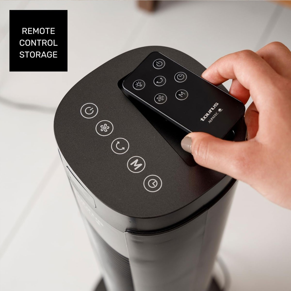 Ręka trzymająca pilota w pobliżu czarnego wentylatora. Pilot ma różne przyciski.