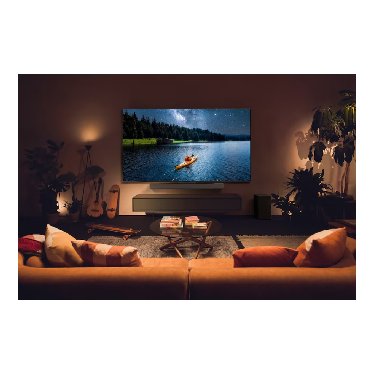Salón con un televisor que muestra una escena de lago. Hay un sofá, una mesa y lámparas.