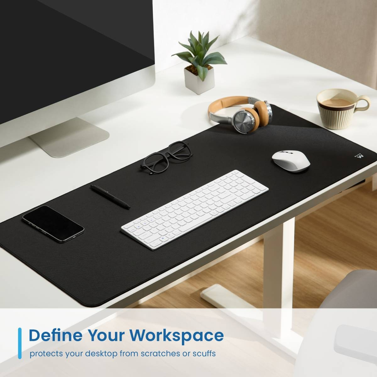 Miejsce pracy z monitorem, klawiaturą, myszą, słuchawkami i rośliną na czarnej podkładce.