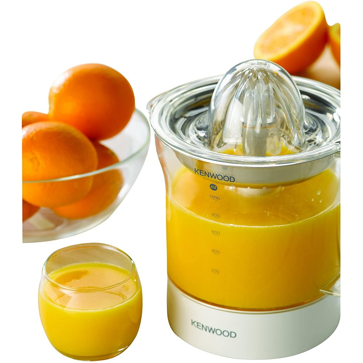 Wyiskarka z sokiem pomarańczowym, pomarańczami i szklanką. Wyiskarka jest w centrum.