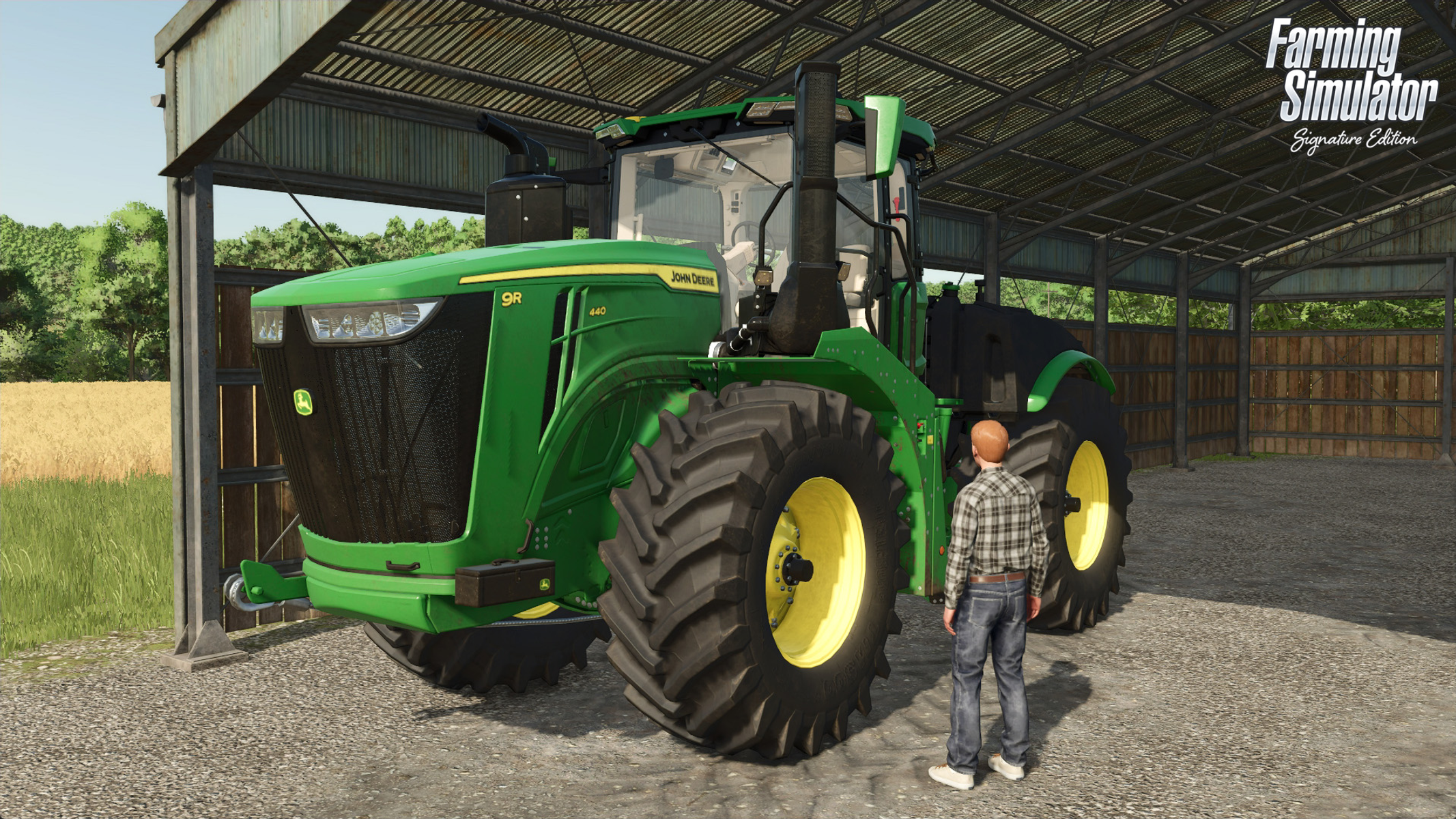 Gran tractor verde en un granero, hombre cerca. Marca John Deere. Luz solar del exterior.