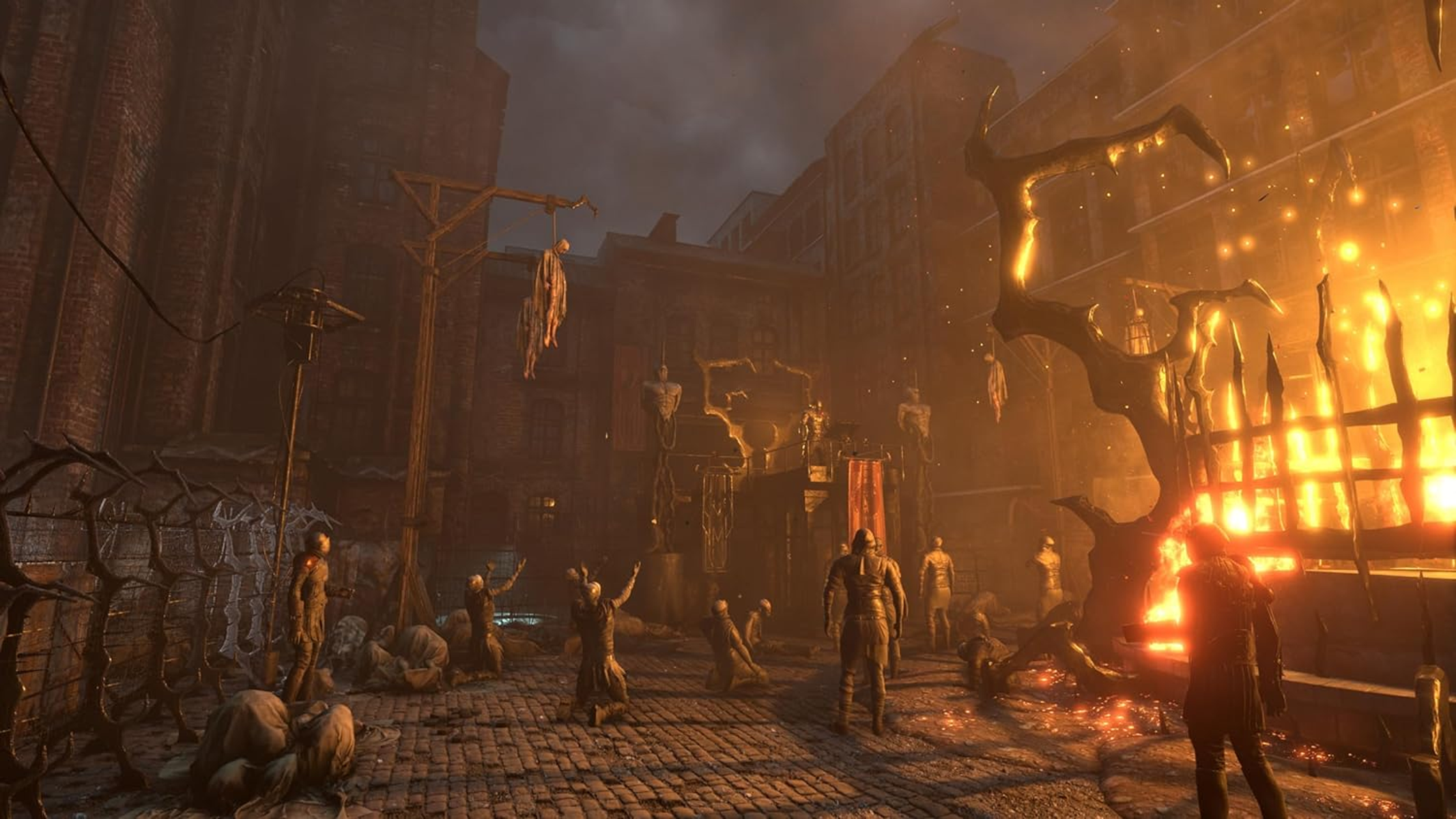 Mroczna scena z postaciami, szubienicami i ogniem. Niebo jest zachmurzone. Scena rozgrywa się na zewnątrz.