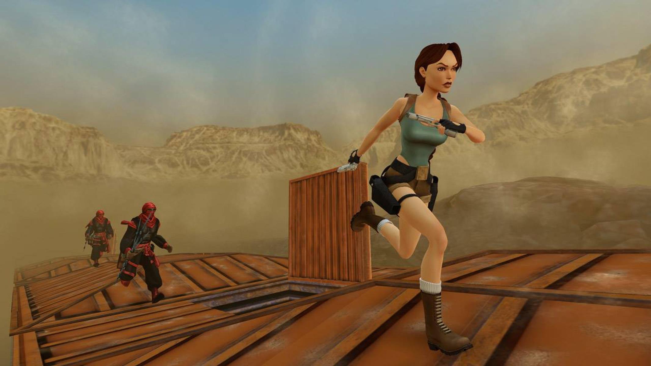 Lara Croft corre su una piattaforma, inseguita da due figure vestite di rosso in un paesaggio desertico.