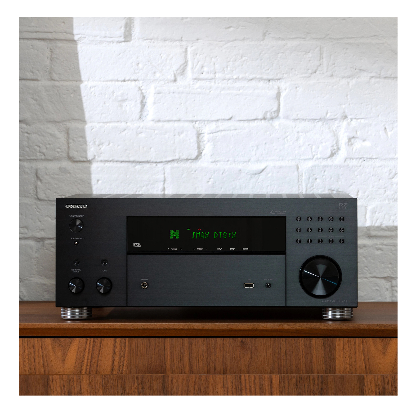 Schwarzer Stereo-Receiver auf Holzschrank, weiße Ziegelwand.