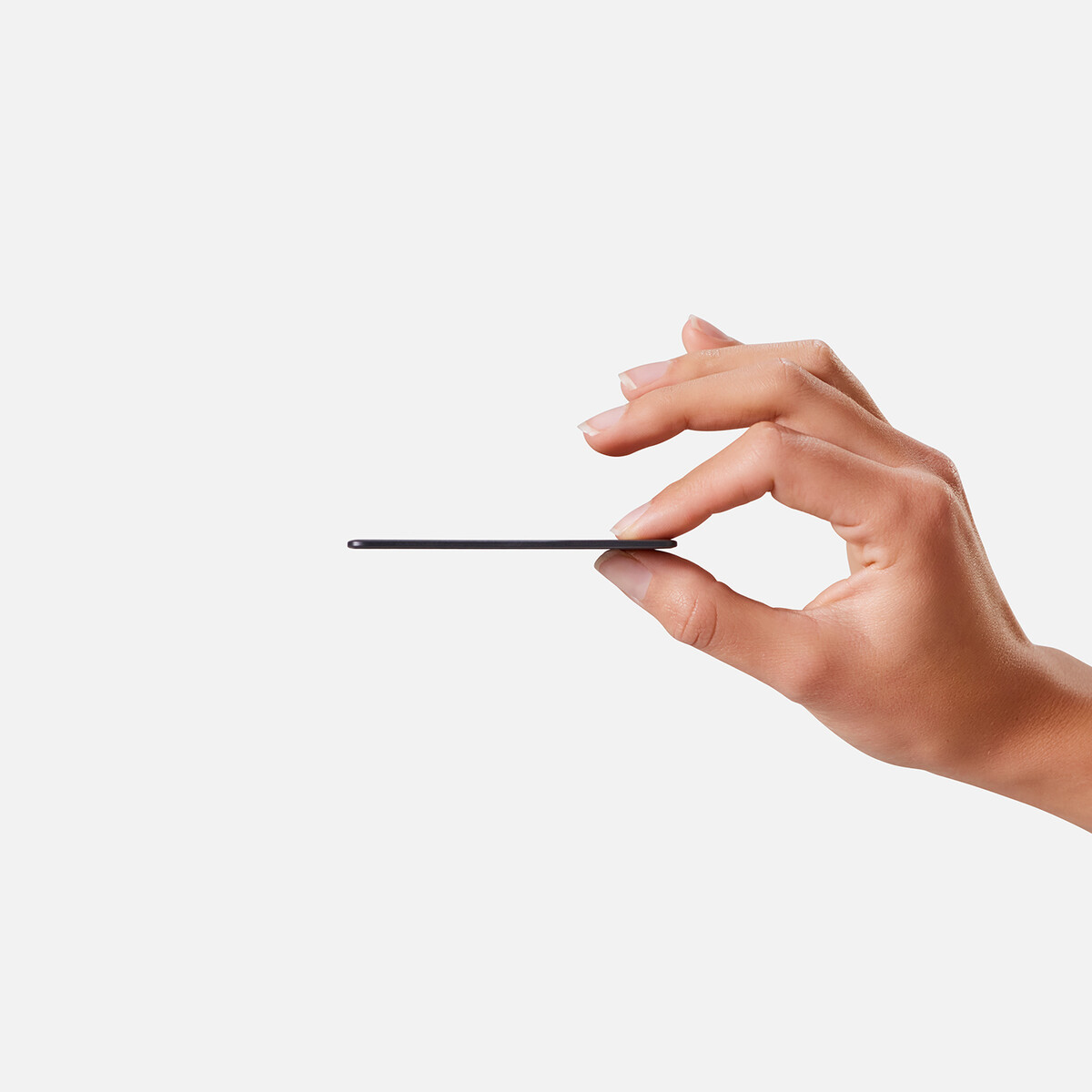 A hand holding a thin, black object, possibly a card, against a white backdrop.